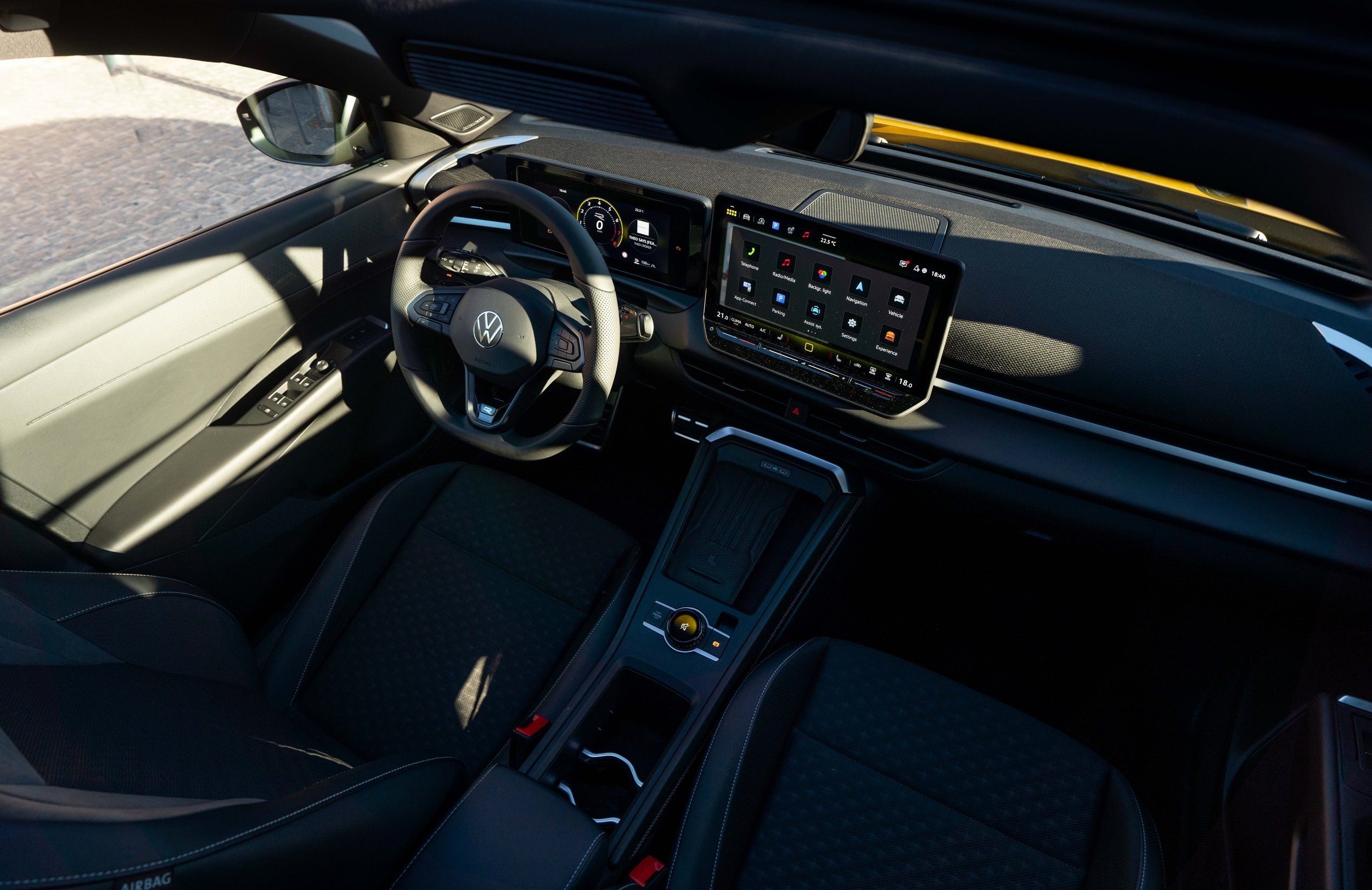 Interior of a Volkswagen electric vehicle showing the steering wheel, digital dashboard, and infotainment screen.