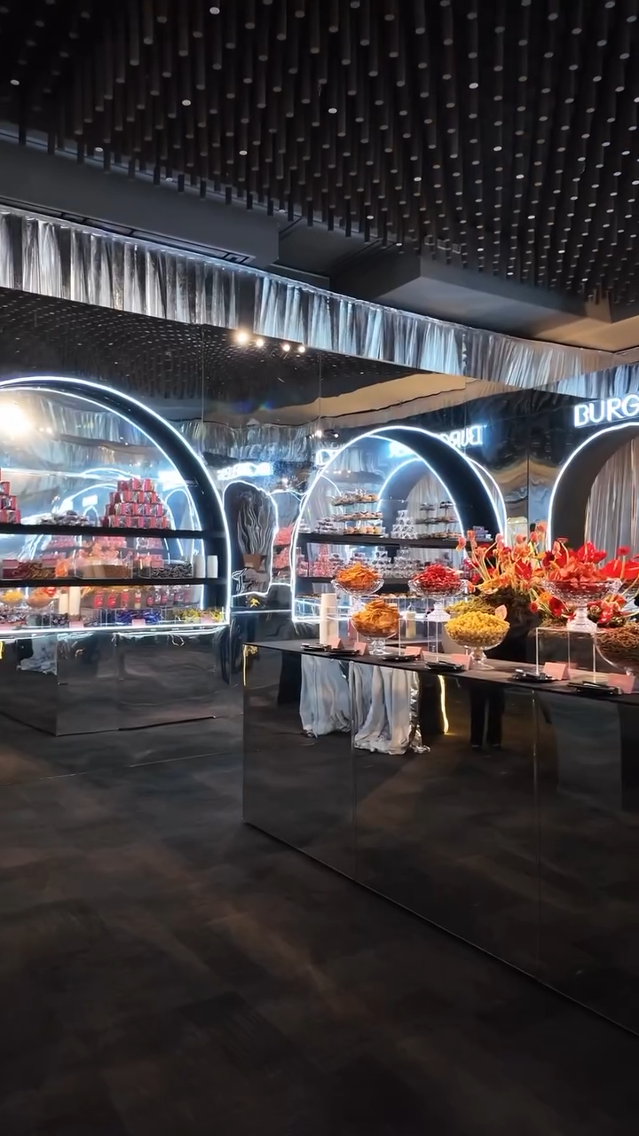 Elegant dessert and snack display in a modern, upscale venue with reflective surfaces and decorative lighting.