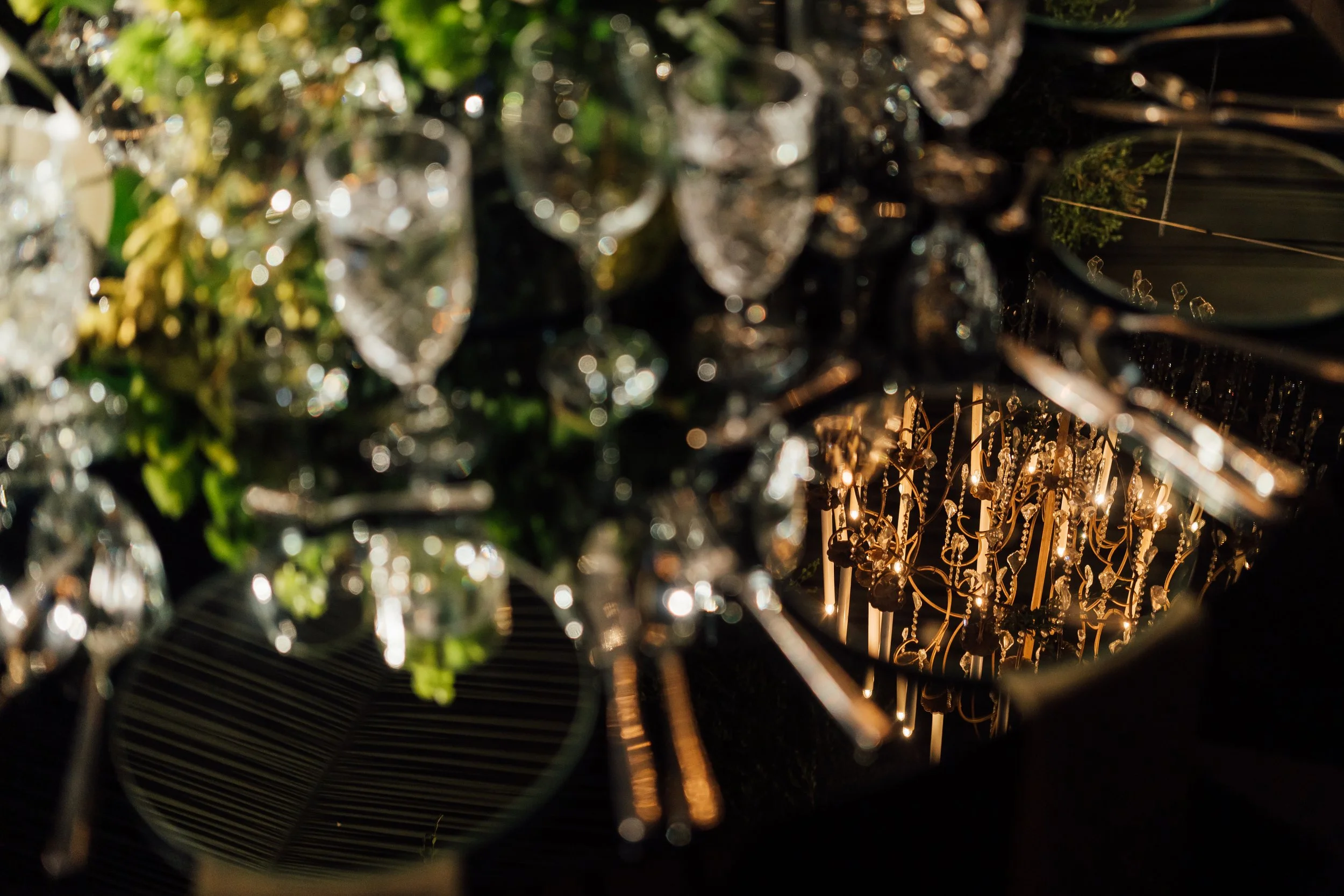 Close-up of hanging crystal chandeliers and reflections on a black surface.