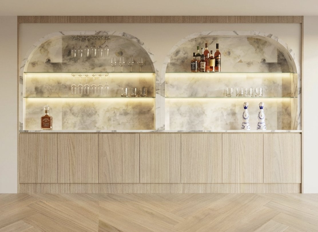 A built-in bar with shelves displaying liquor bottles, glassware, and decorative items, illuminated by soft lighting.