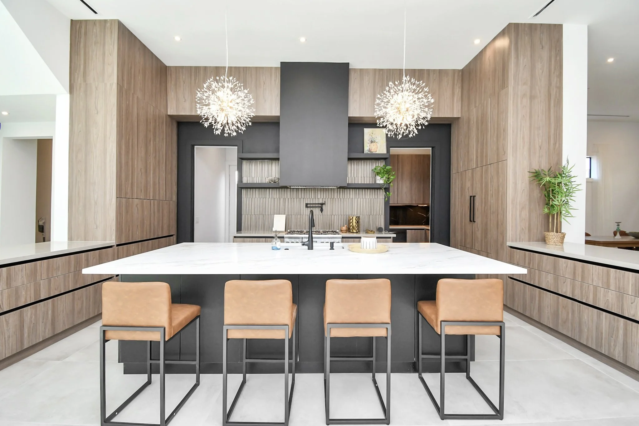 A refined modern kitchen featuring a statement waterfall island, custom wood cabinetry, and sculptural lighting—designed for both elevated living and effortless entertaining.