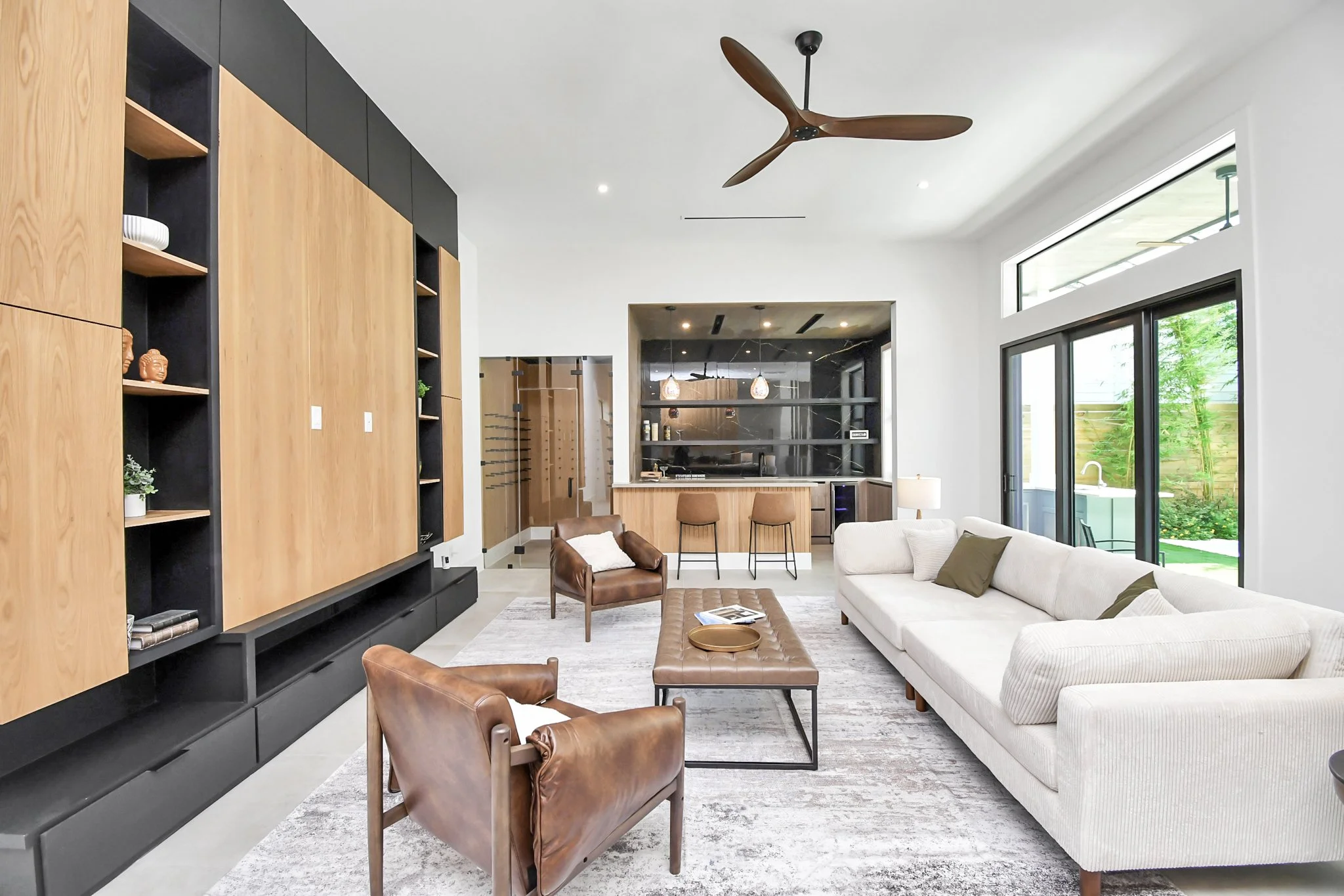 A refined lounge space with custom built-ins, rich wood accents, and seamless flow into a private bar—designed for sophisticated entertaining and relaxed living.