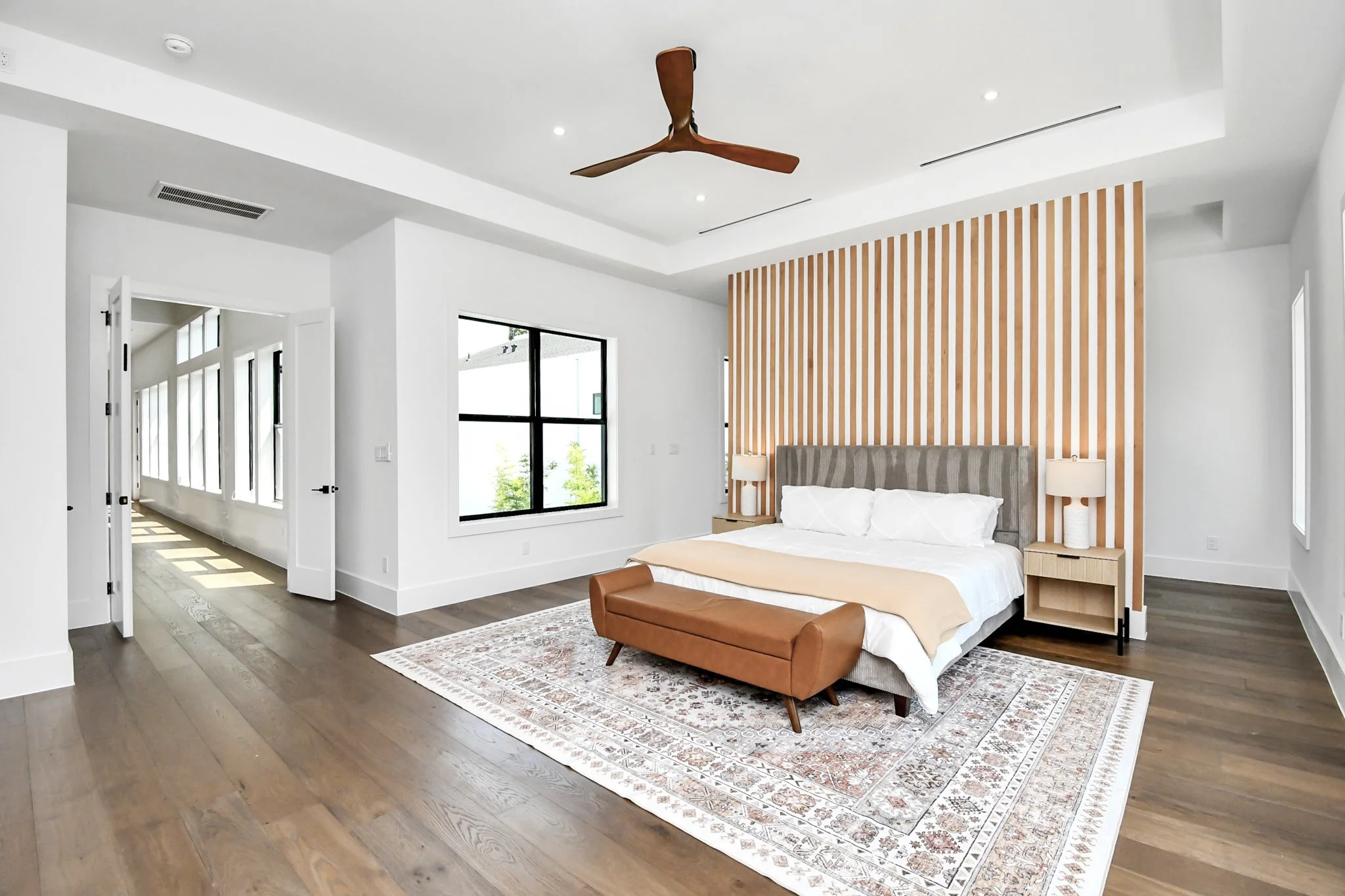 A serene primary suite featuring warm wood accents, clean architectural lines, and abundant natural light—designed as a private retreat for rest and relaxation.