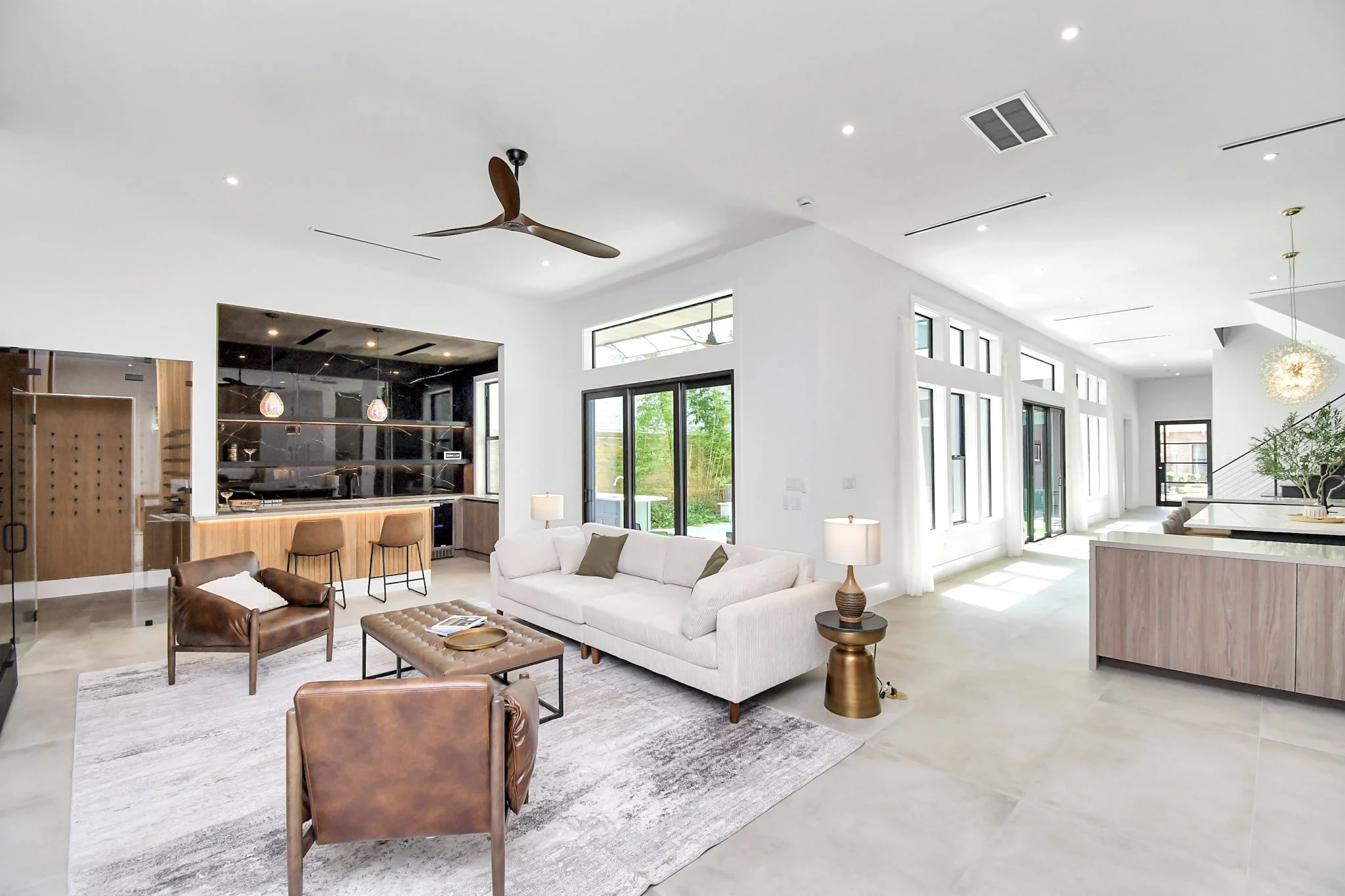 A bright, architecturally clean living space defined by expansive glass, warm textures, and a seamless connection between indoor comfort and outdoor living.