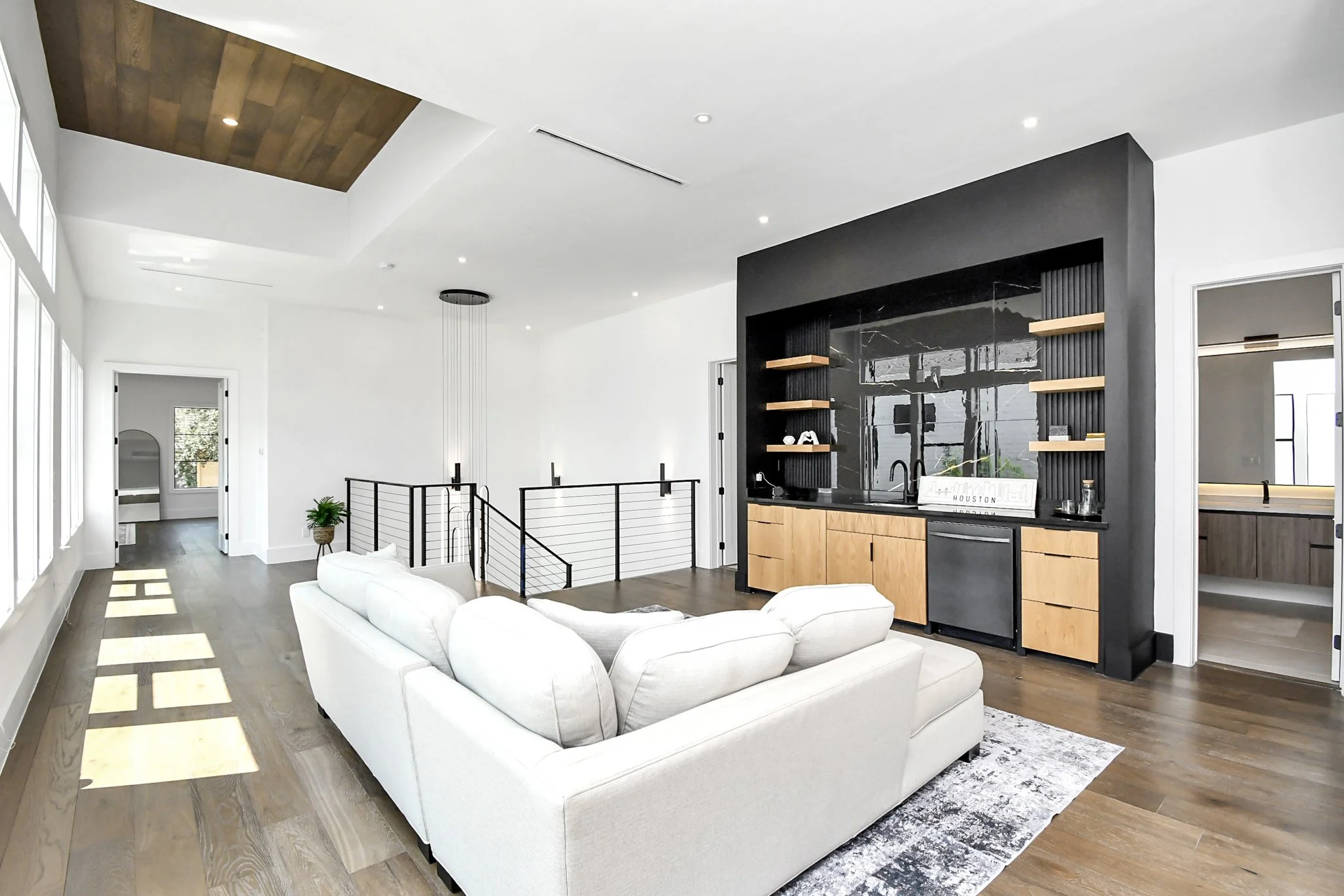 A sophisticated living space featuring warm wood floors, a custom built-in bar, and expansive natural light—designed for both relaxed living and refined entertaining.