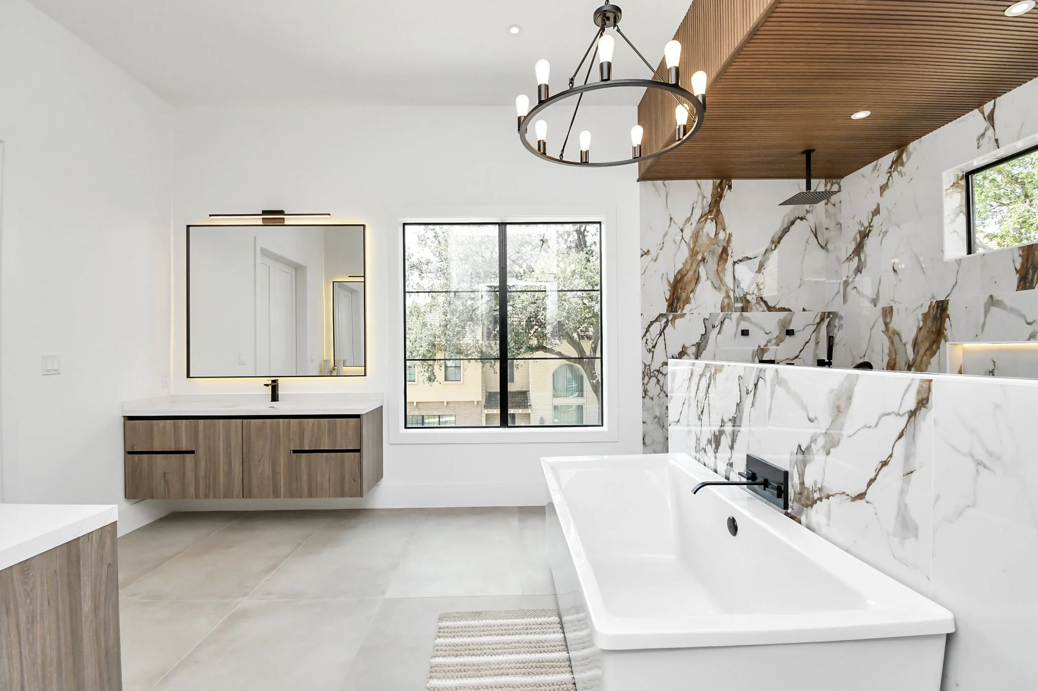 A statement bathroom defined by bold marble walls, a freestanding soaking tub.