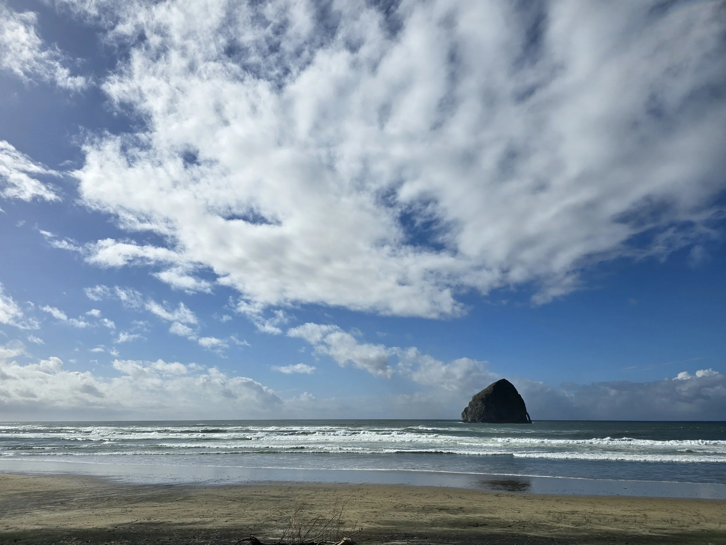 Blue sky with white clouds over ocean and Haystack rock