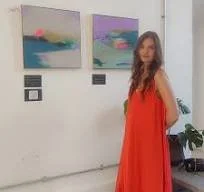 Woman in red dress standing in front of abstract paintings on a gallery wall