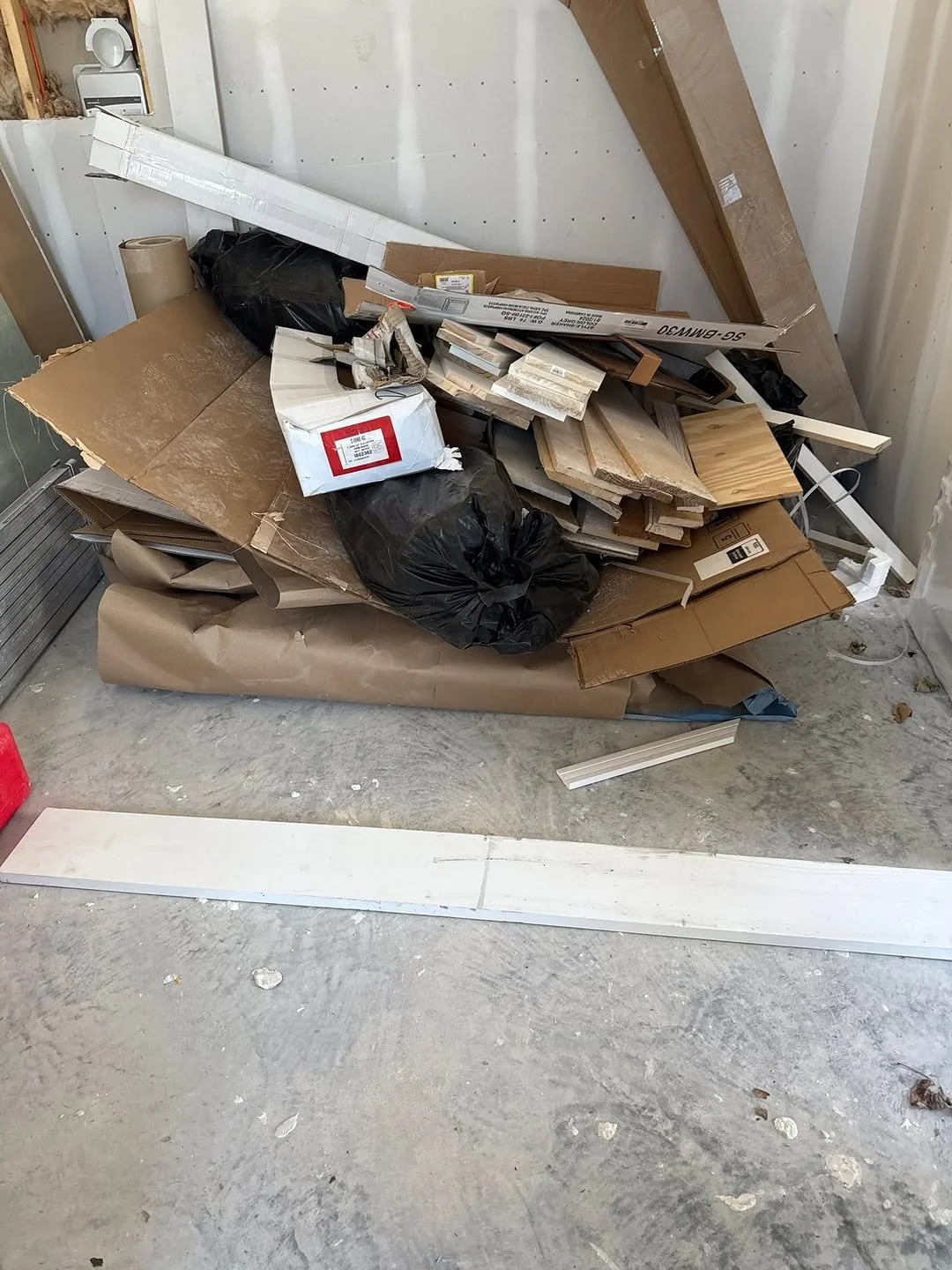 Pile of discarded cardboard, wood, and construction materials in a partially finished room.
