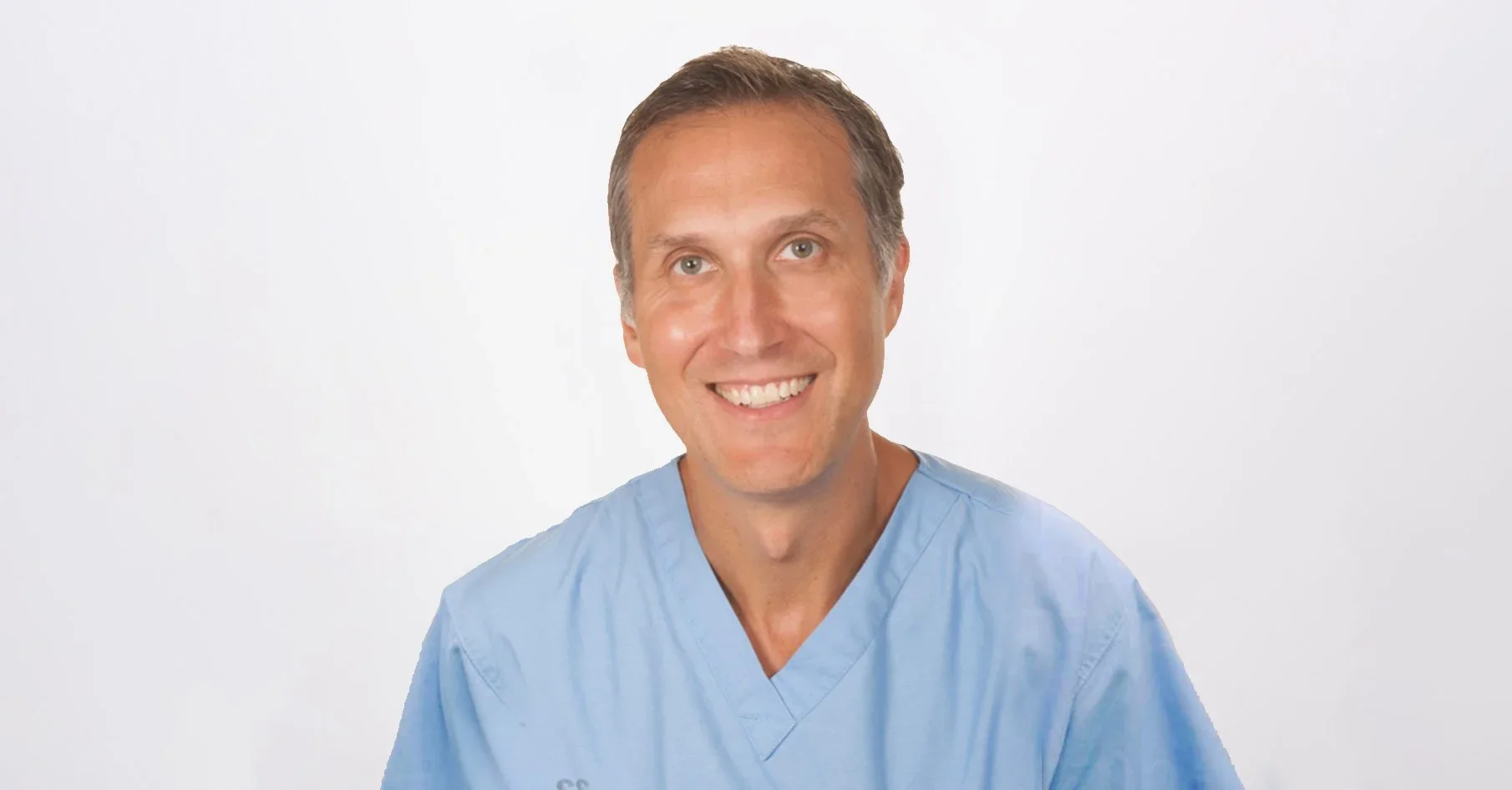 Smiling man wearing medical scrubs against a plain white background. Moishe Liberman