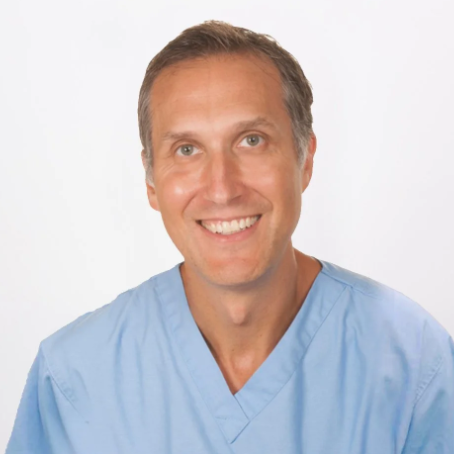 Prof. Moishe Liberman- A man wearing light blue medical scrubs, smiling, with a plain white background.
