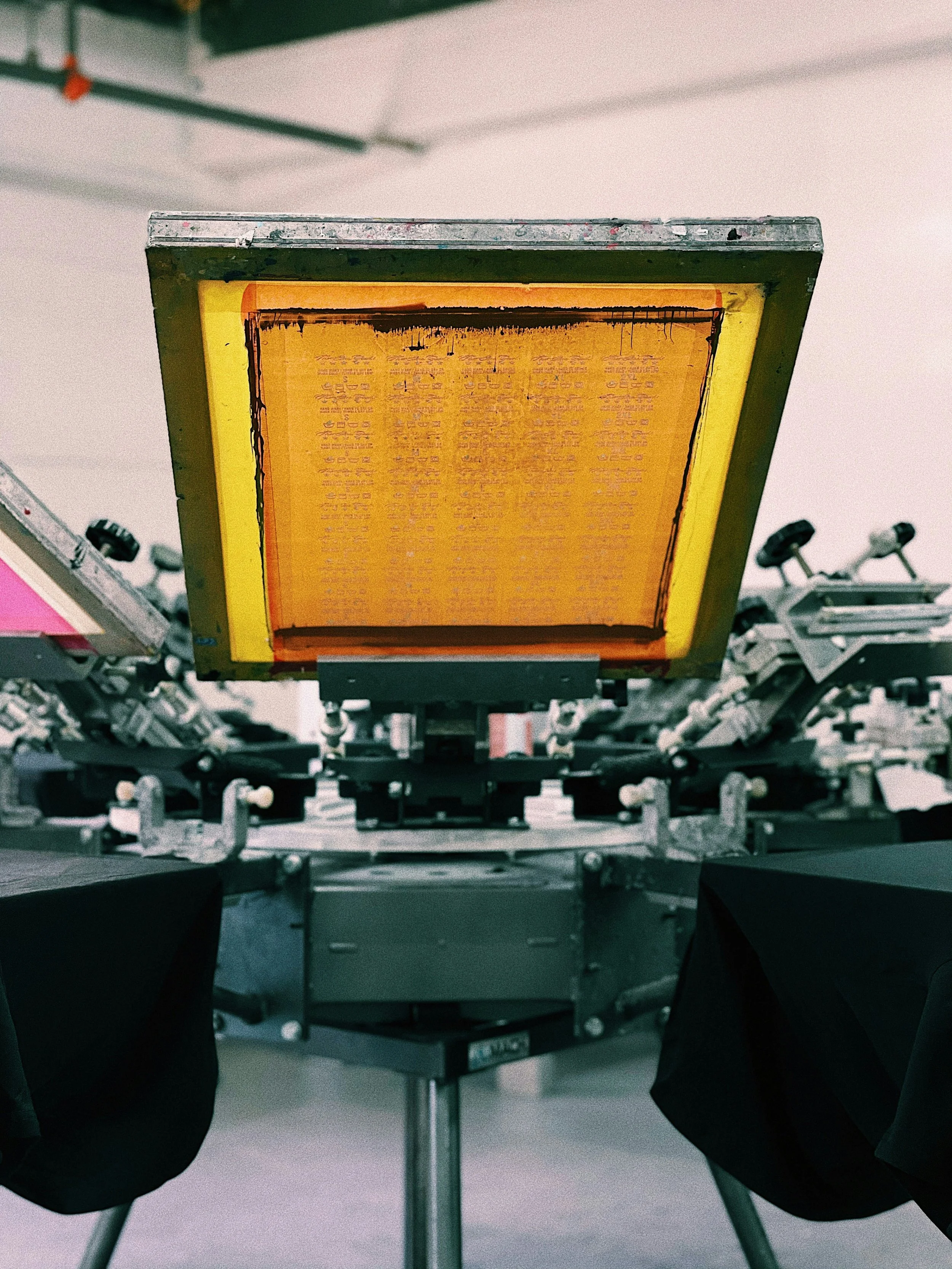 A light box illuminated with an orange glow, surrounded by manufacturing equipment, with black fabric or material beneath it.