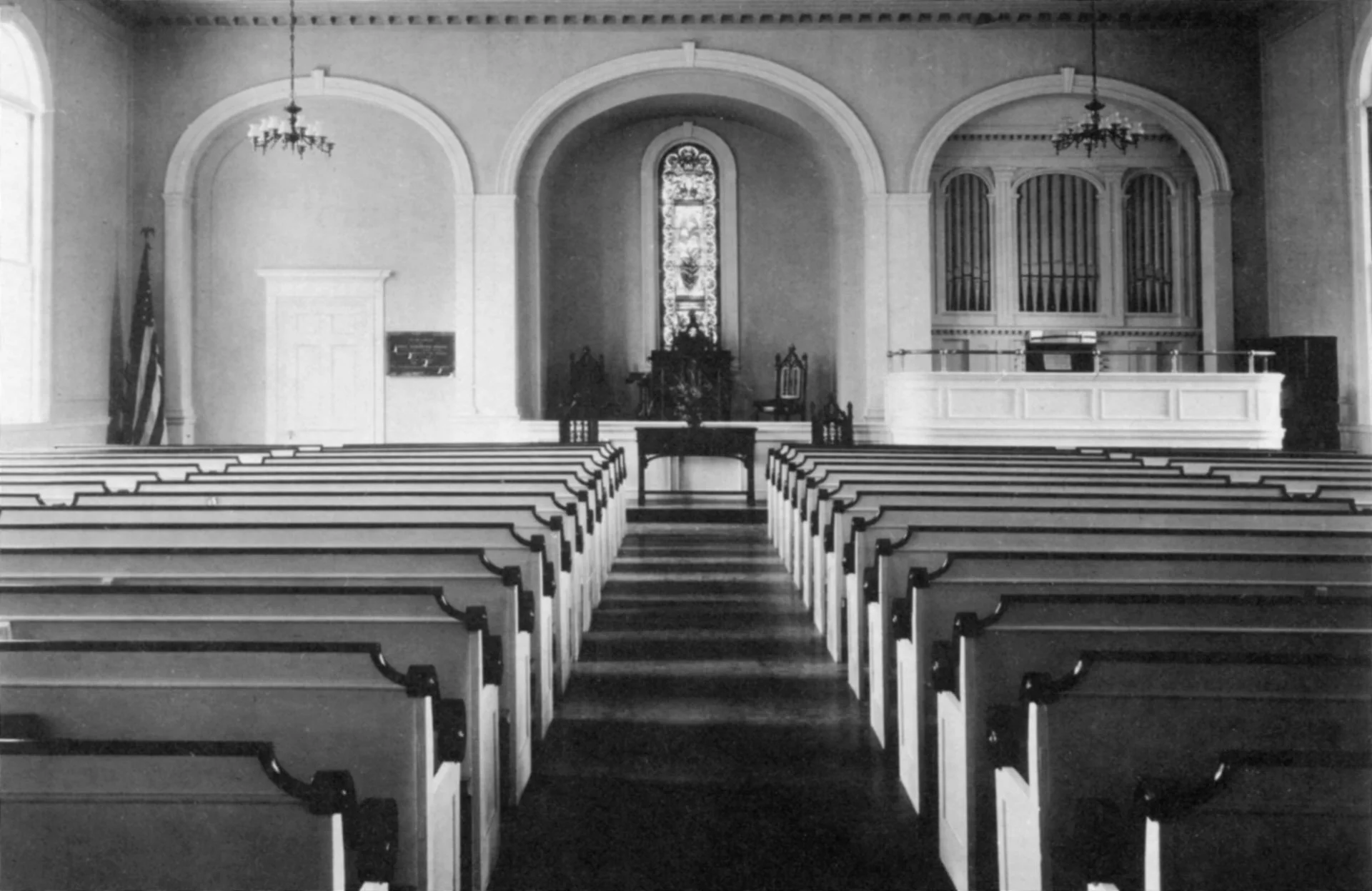 The Sanctuary in 1931 with stained glass window and singing seats.