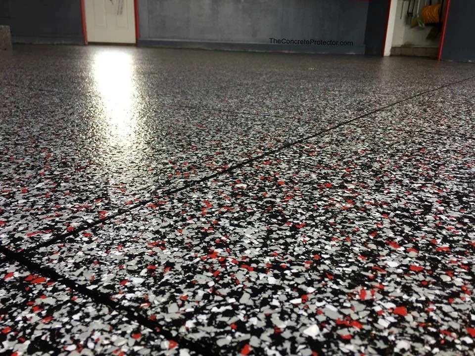 Close-up view of a decorated, shiny, speckled flooring with black, white, and red flecks, 
red black and white chip flake epoxy with a polyuria top coating