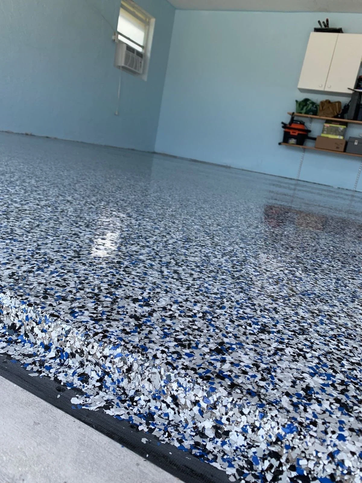 Close-up of a freshly poured epoxy garage floor with blue, white, and black flakes