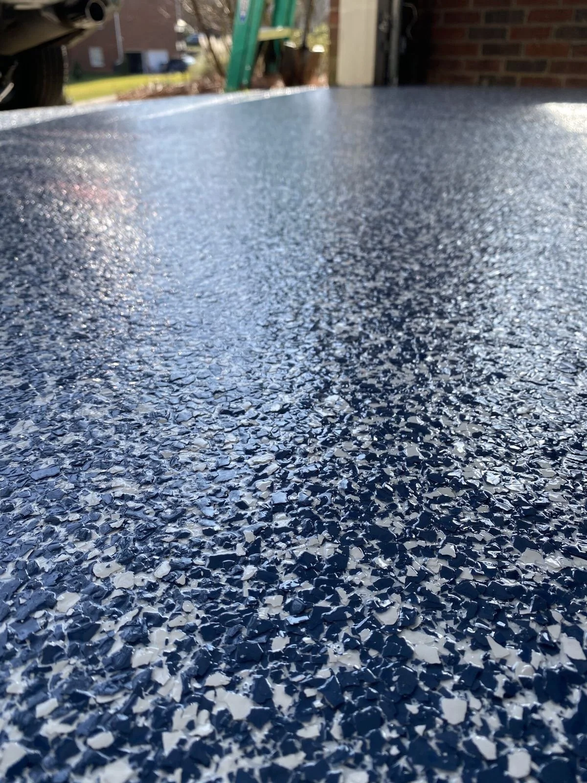 Close-up of a textured, chip flake epoxy floor in a garage with blue white and black colors 