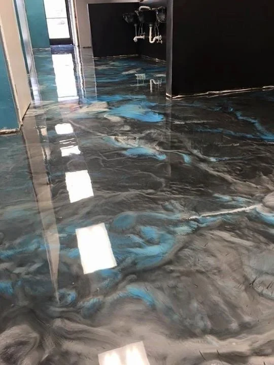 high gloss and polished metallic epoxy floor with dark black and grey with a teal accent color 