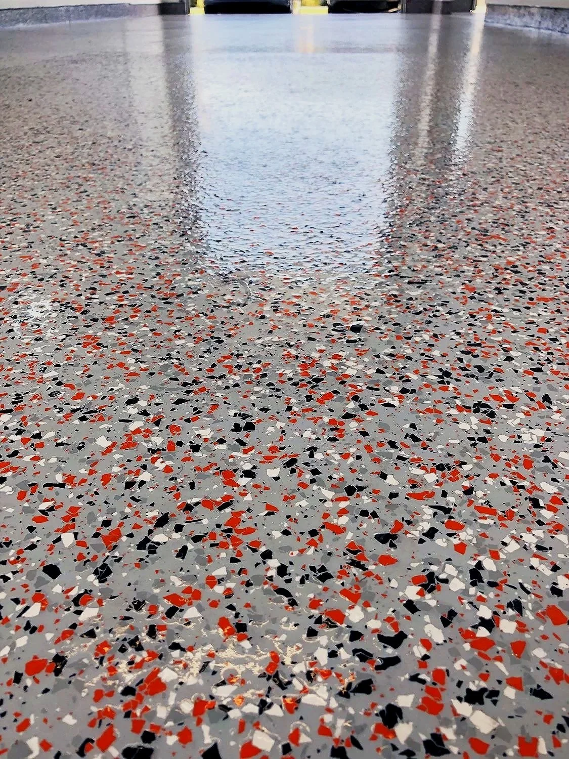 red black and beige epoxy chip flake flooring inside of garage with multiple top coats of polyaspartic coatings