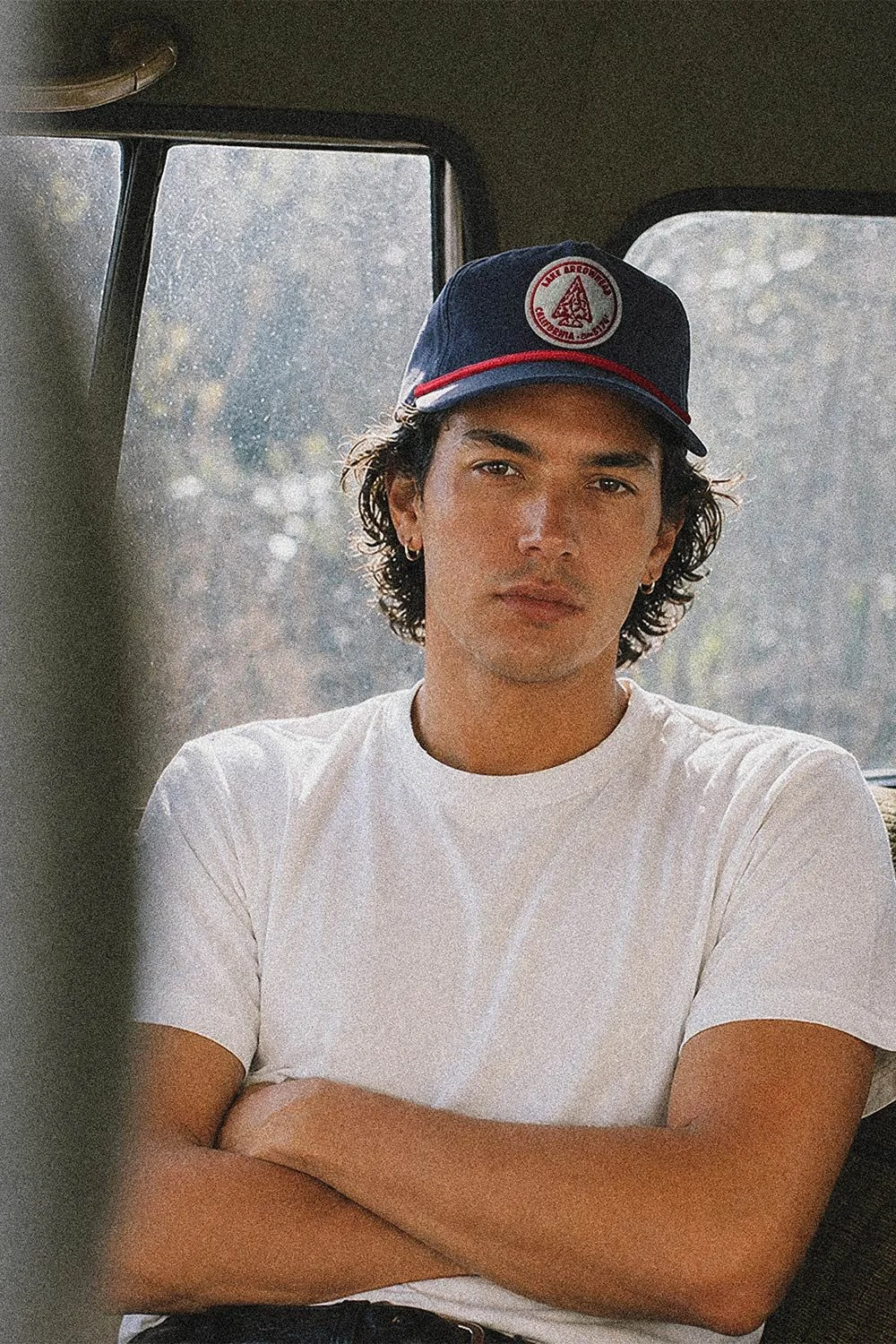 man in a car wearing a lake arrowhead hat