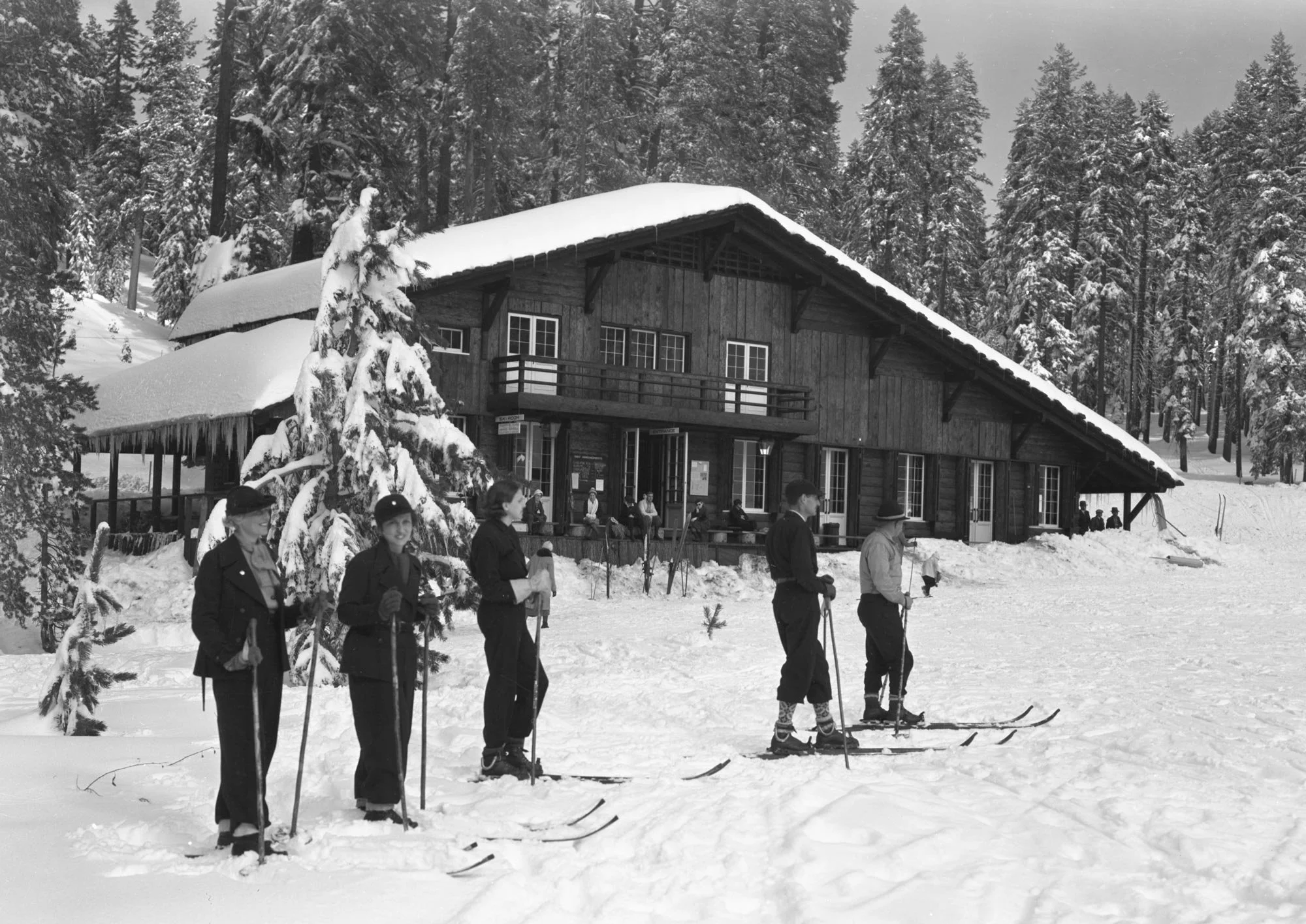Skiers standing outside the snow-covered Badger Pass Ski House in Yosemite National Park in 1936.