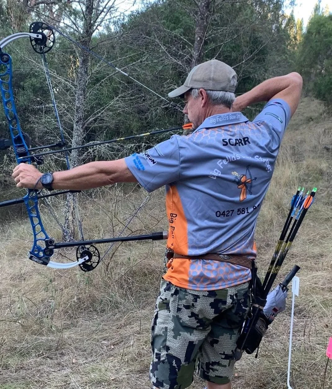 A man practicing archery outdoors, aiming with a bow and arrow.