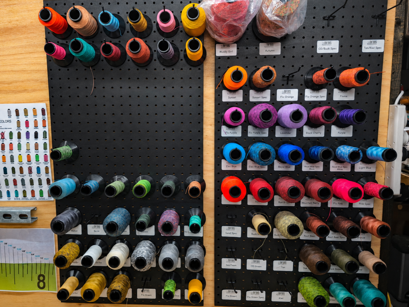 A display of colorful fishing line spools organized on a black pegboard.