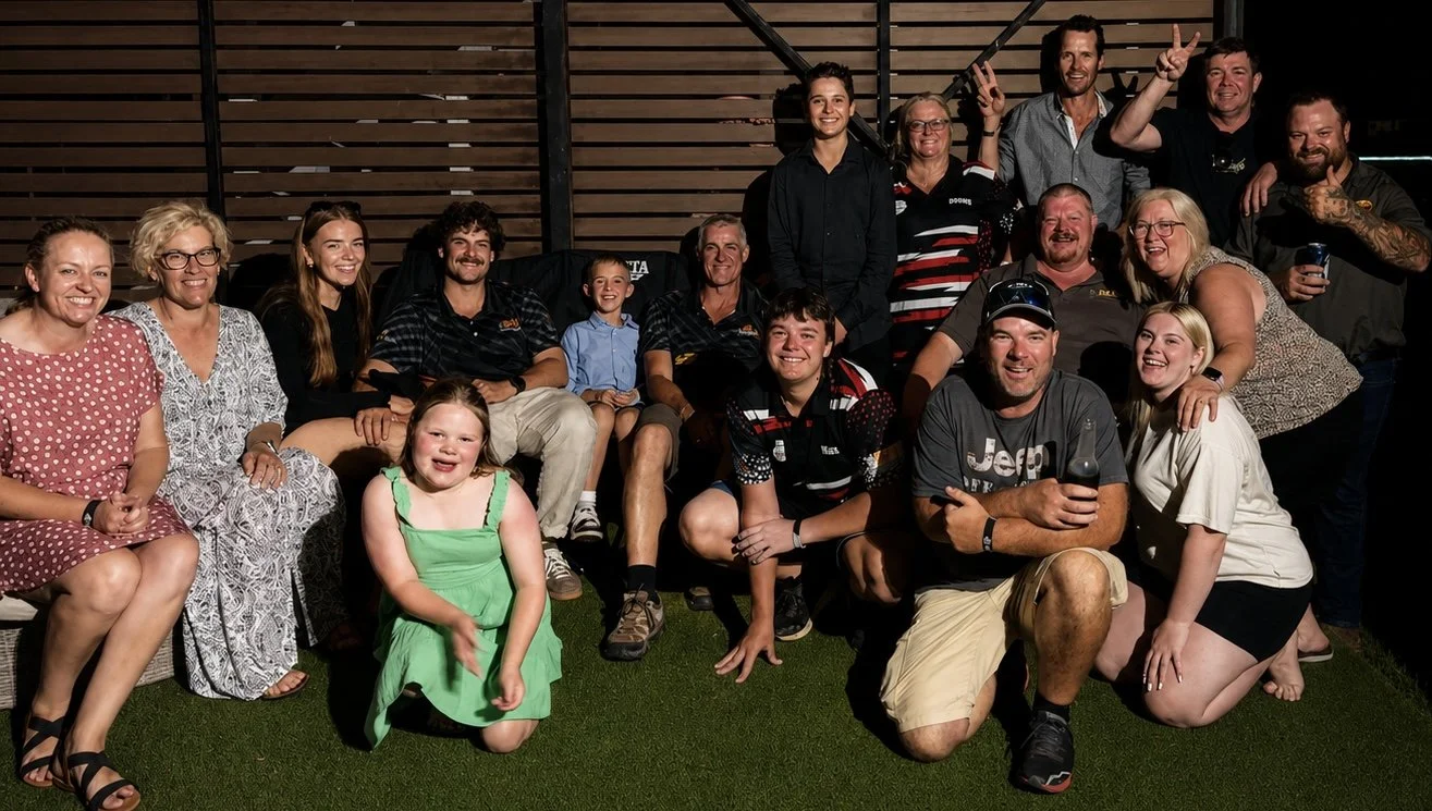 A group of 16 happy archers, including children and adults, smiling and posing for a group BFBS photo.