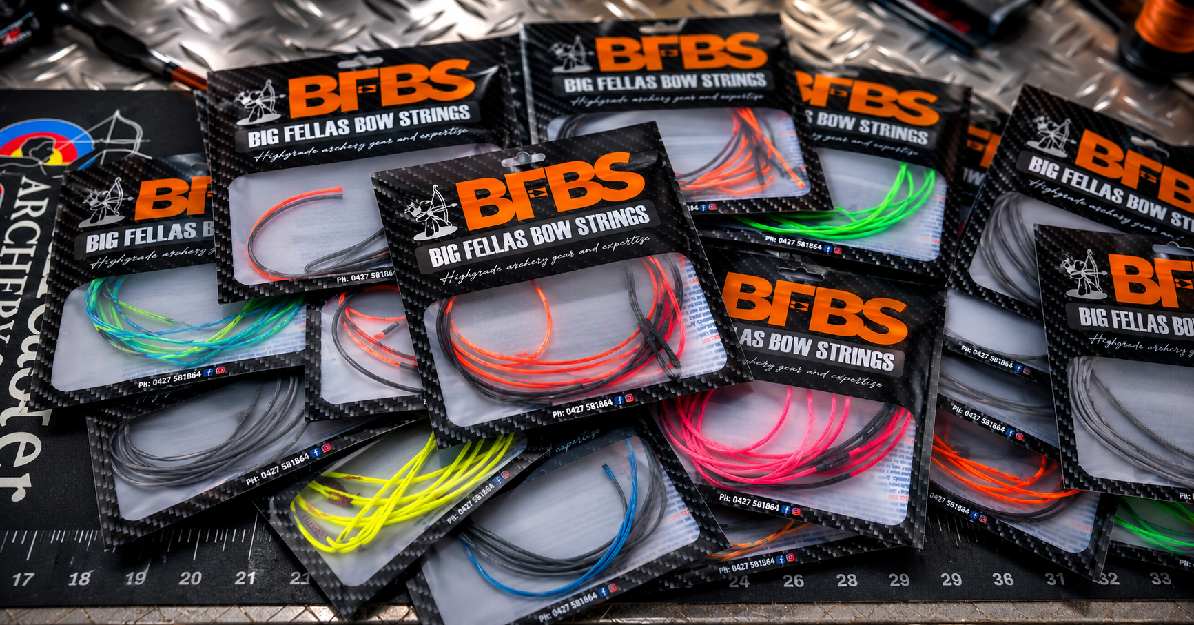 Multiple packages of Big Fellas Bow Strings in various colors displayed on a work surface.