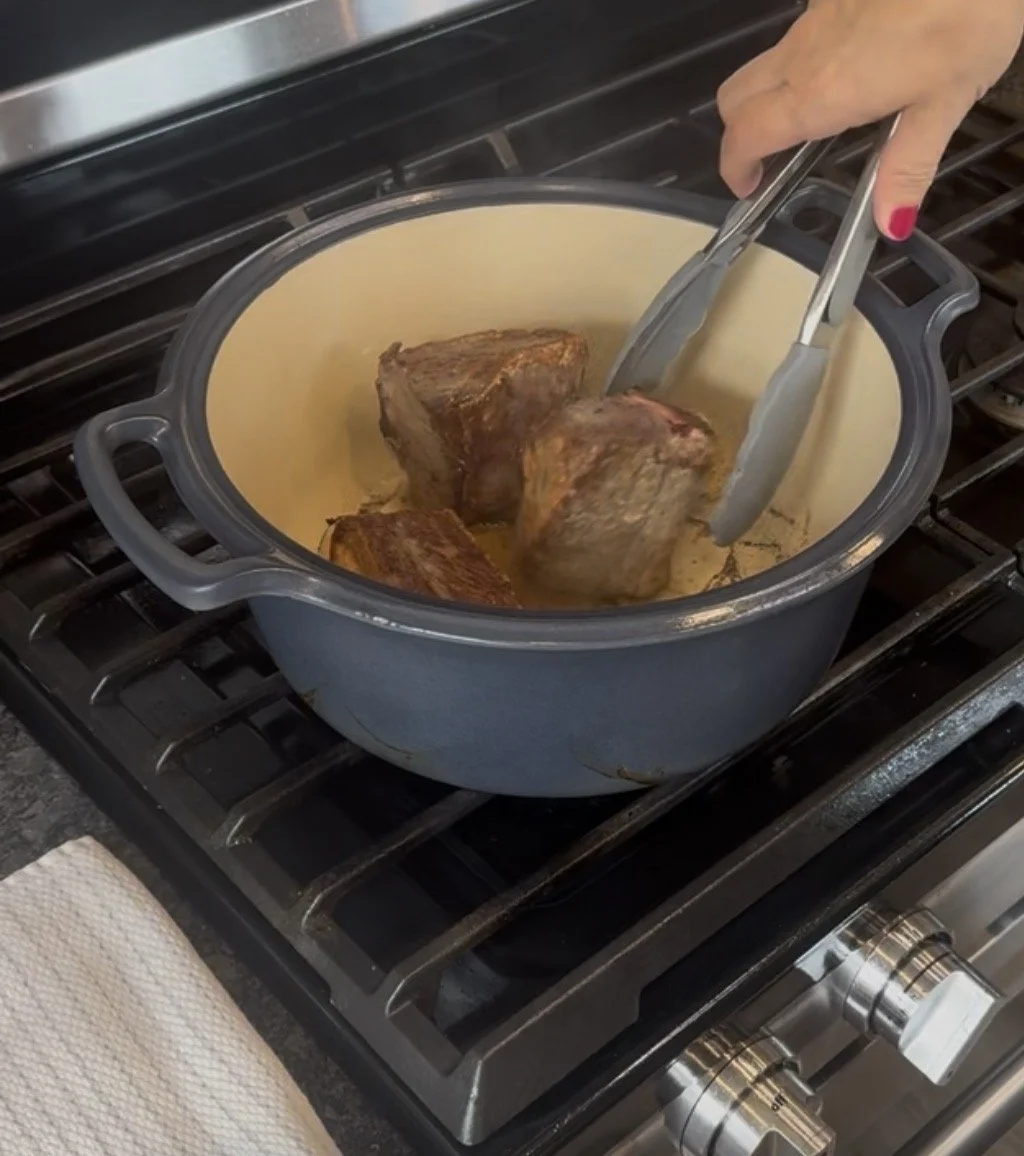 Short ribs browning on all sides in a dutch oven on the stovetop.