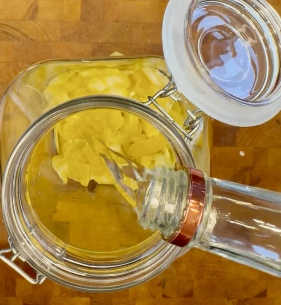 Pouring vodka over lemon peels in a glass jar to make homemade limoncello.