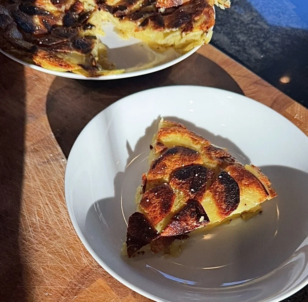 A sliced wedge of Pommes Anna on a plate, layers of caramelized potatoes