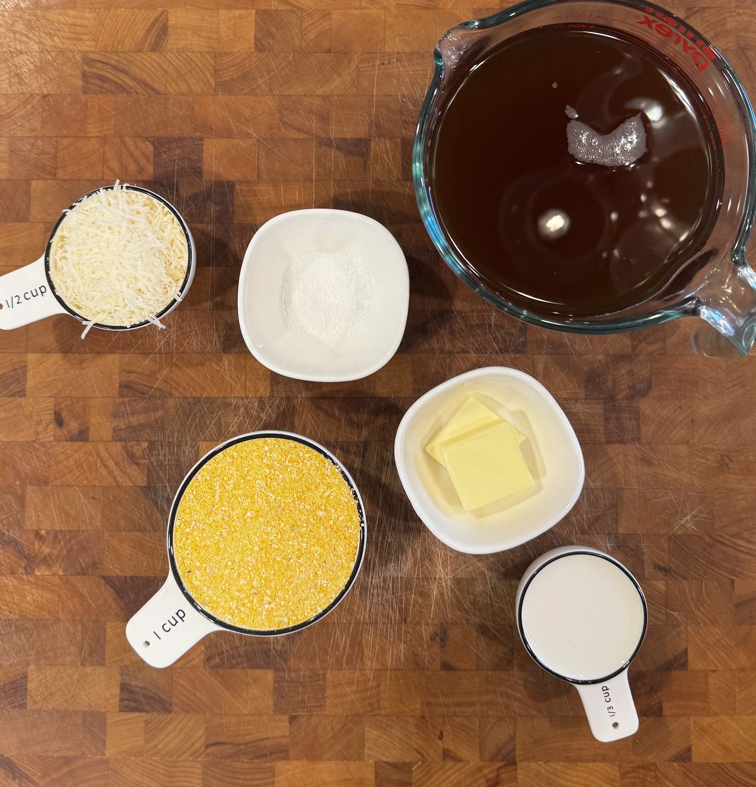 Ingredients for creamy polenta including polenta, beef broth, butter, milk, salt, and grated Parmigiano Reggiano