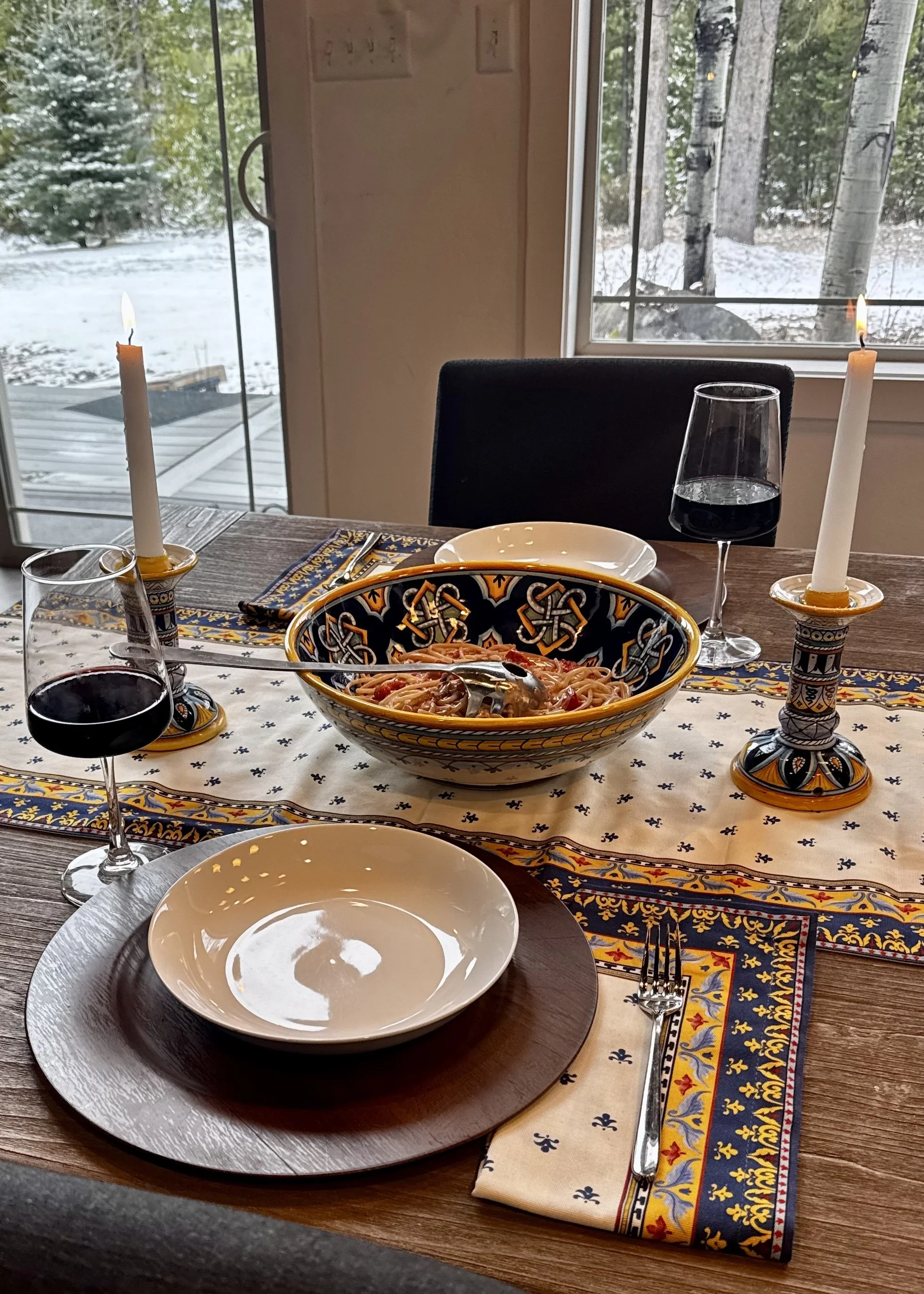 Bowl of red wine tomato cream pasta on a candlelit table with red wine, overlooking snowy mountain view at Whiskey Ridge