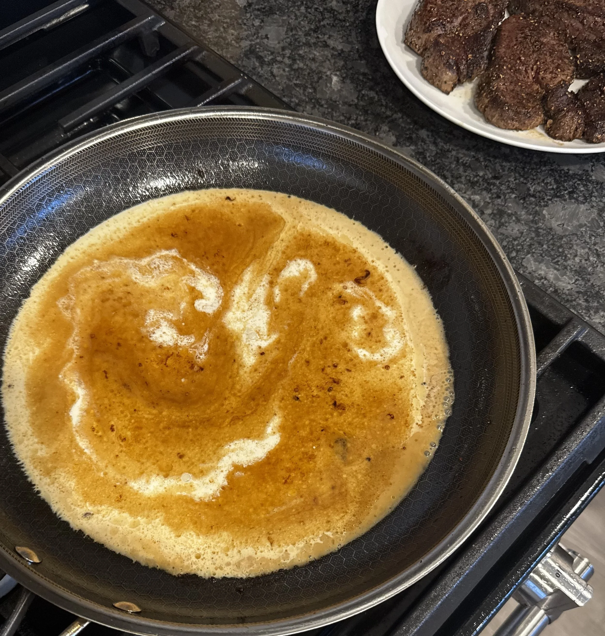 Cognac cream sauce reducing in the pan for Whiskey Ridge Steak au Poivre.