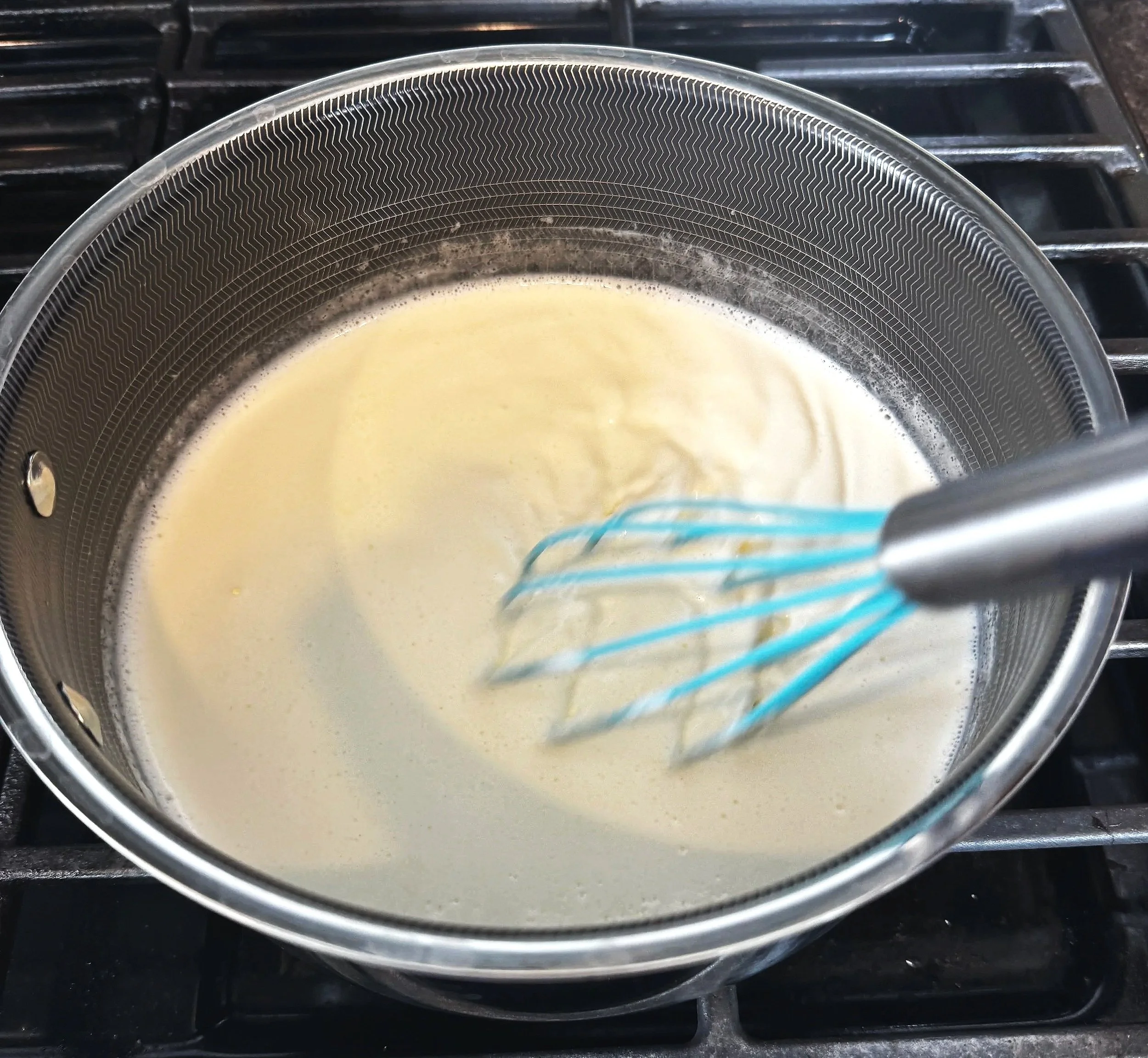 Cooking vanilla ice cream custard on the stove while stirring with a whisk