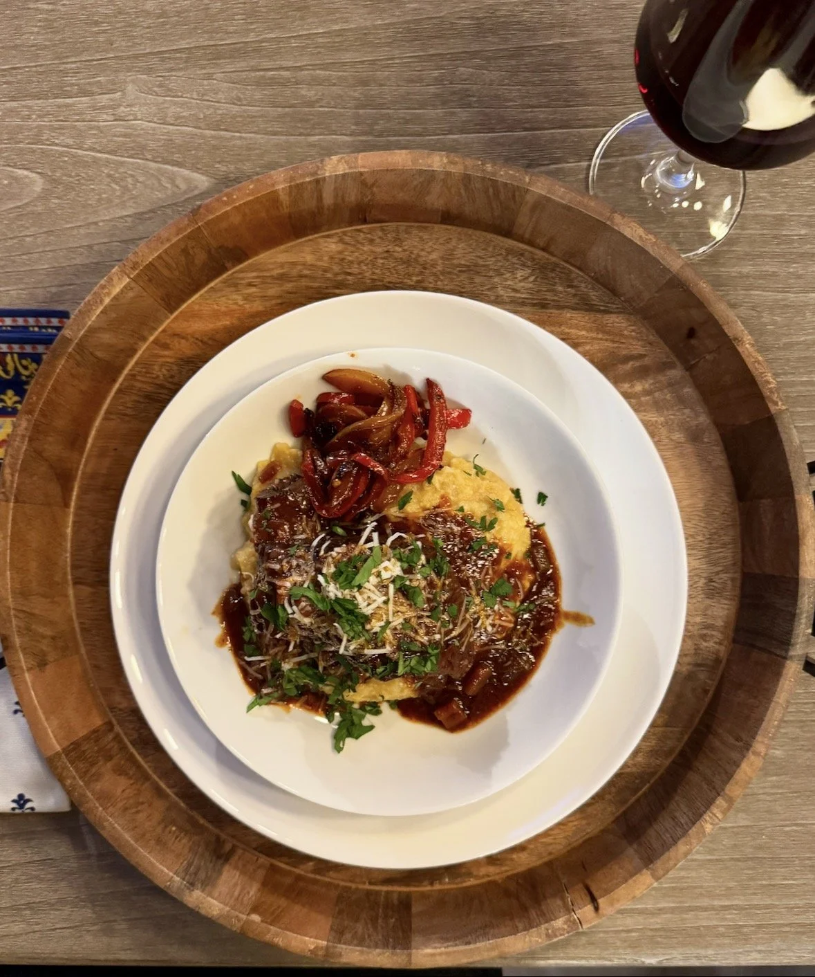 Braised short ribs served over creamy polenta with grated Parmigiano Reggiano on a white plate