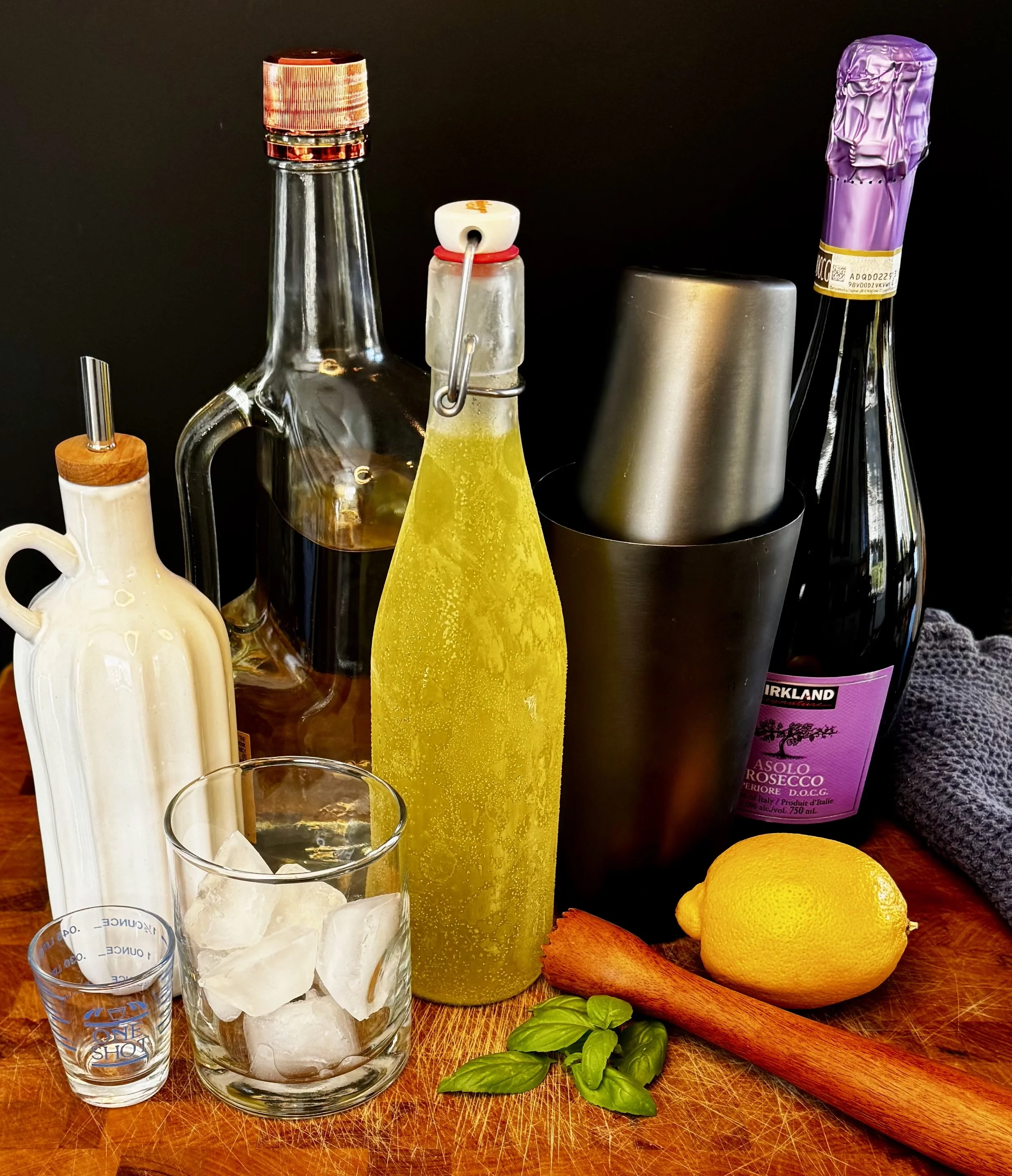 Ingredients for an Almalfi Basil Smash cocktail including limoncello, vodka, lemon, basil, and prosecco.