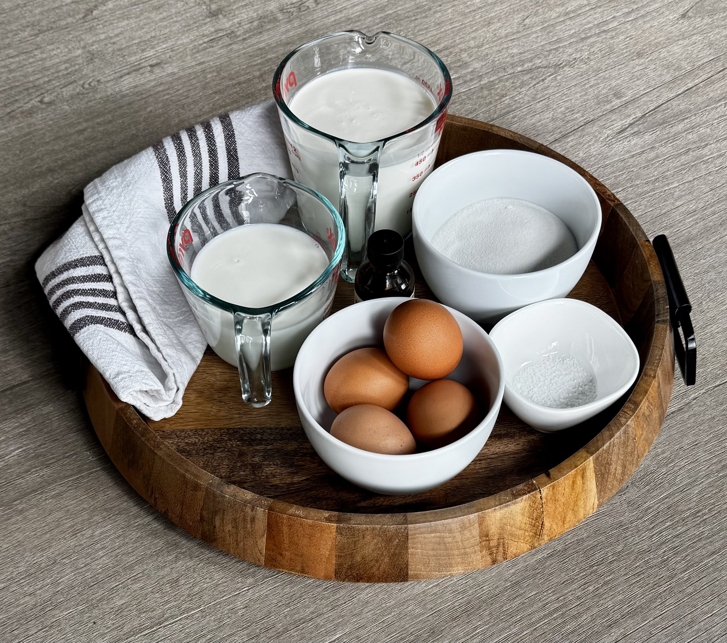 Ingredients for homemade vanilla ice cream including cream, milk, sugar, egg yolks, and vanilla