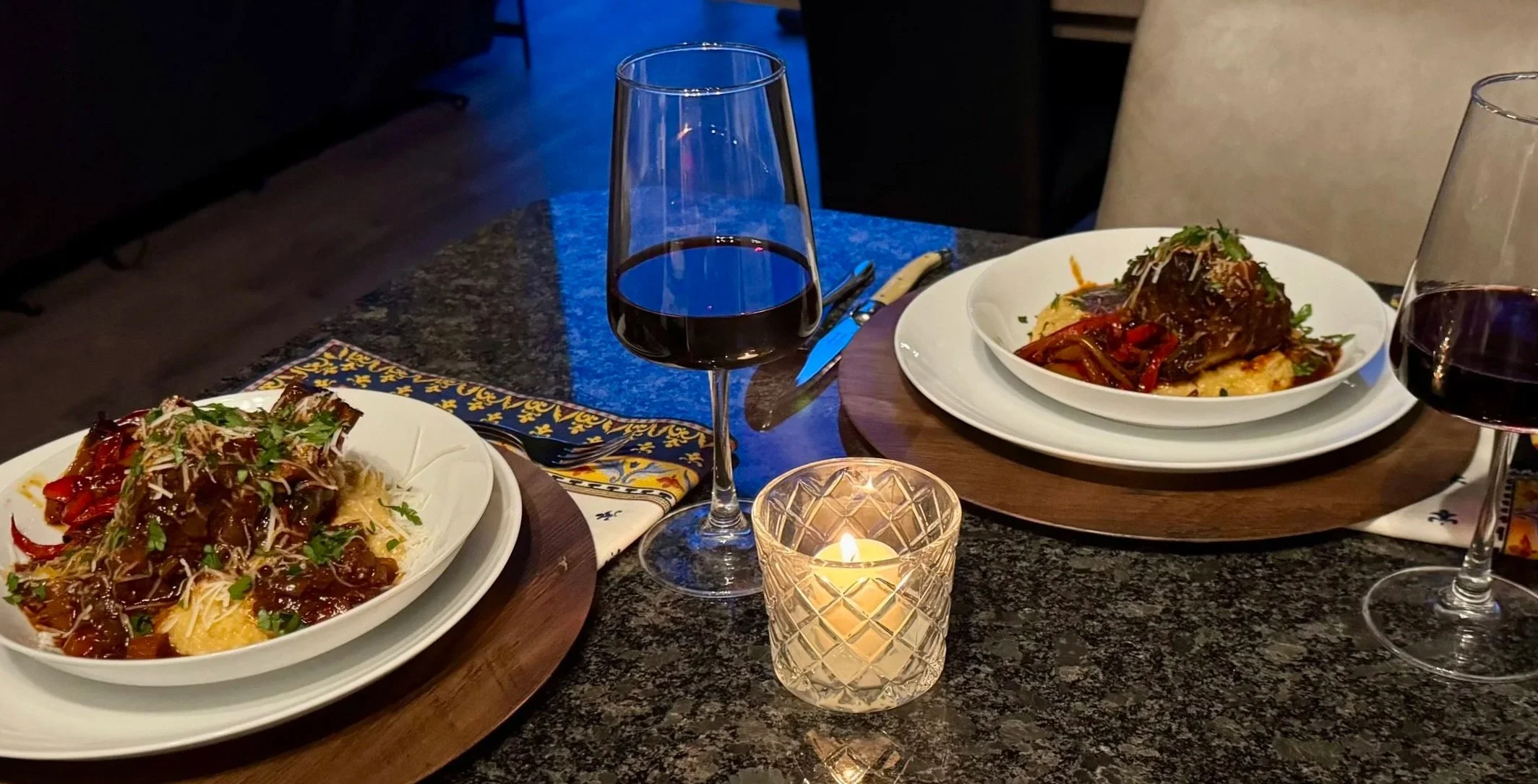 Dinner table with braised short ribs over polenta and glasses of red wine
