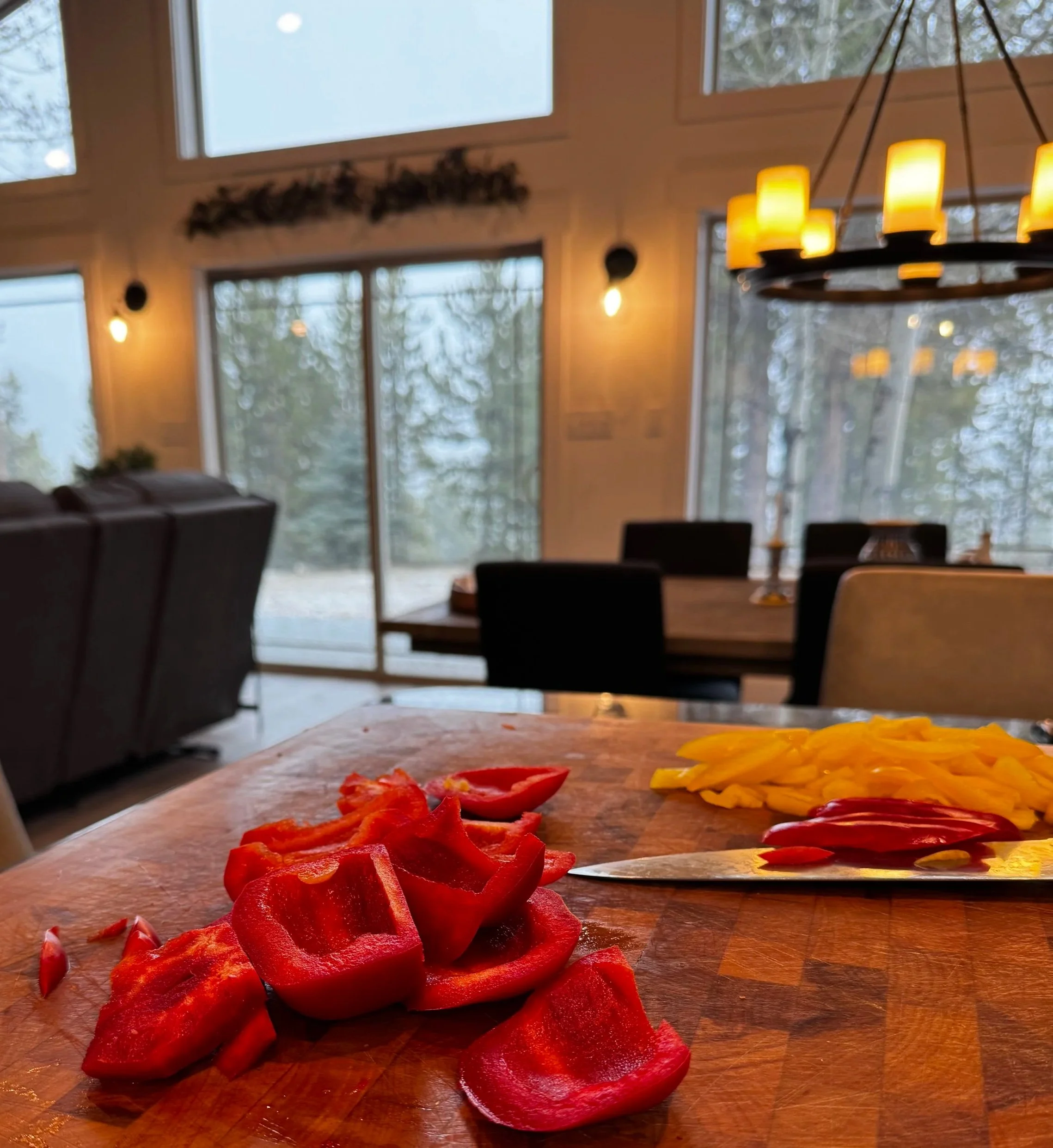 Cutting fresh bell peppers on a wooden board in a mountain kitchen