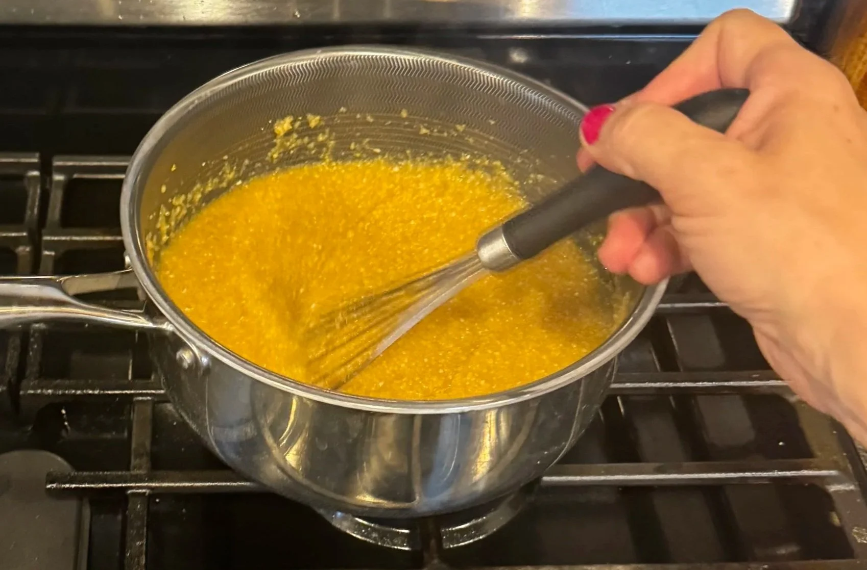 Whisking polenta in saucepan on stovetop