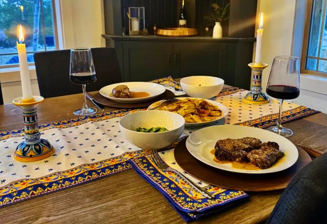 Steak au Poivre with cognac cream sauce, Pommes Anna, and green salad served by candlelight at Whiskey Ridge with red wine and Provencal table runner.