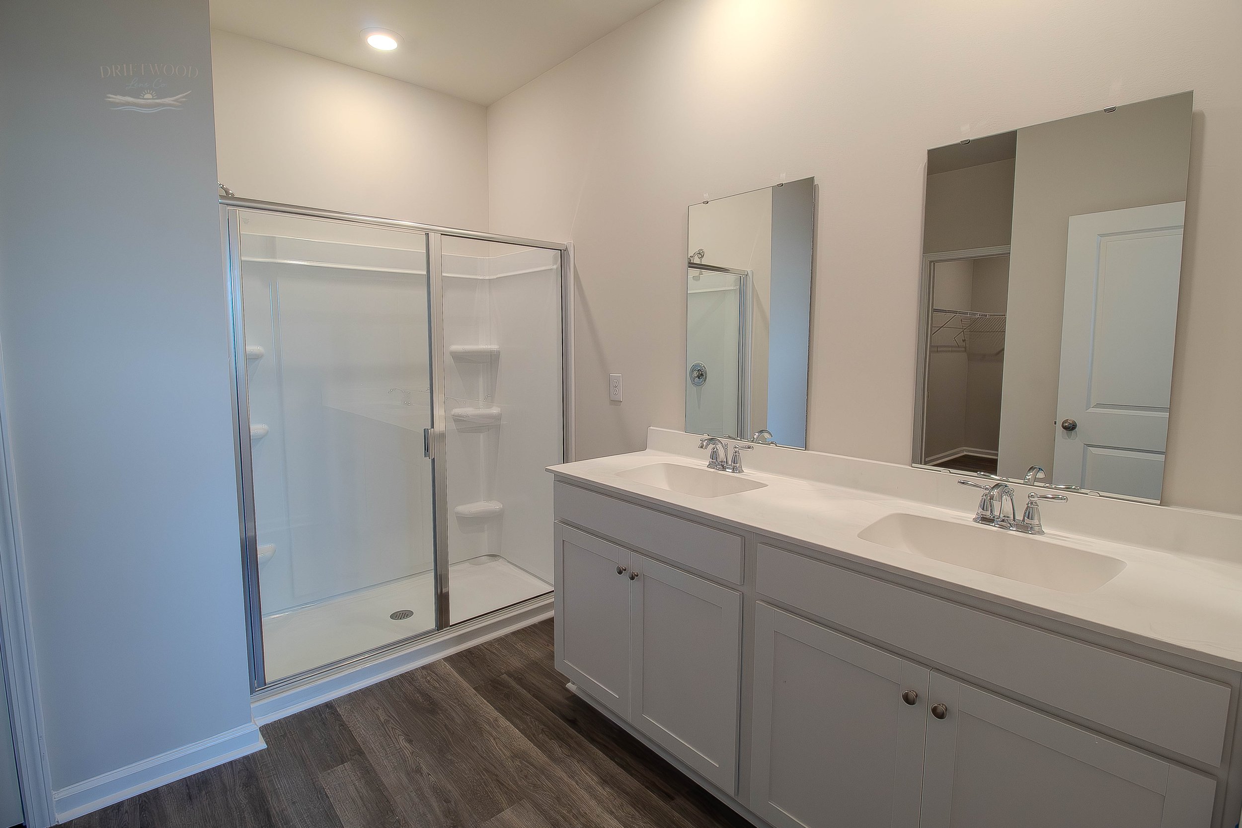 Bathroom with a double vanity, two mirrors, and a glass shower enclosure.