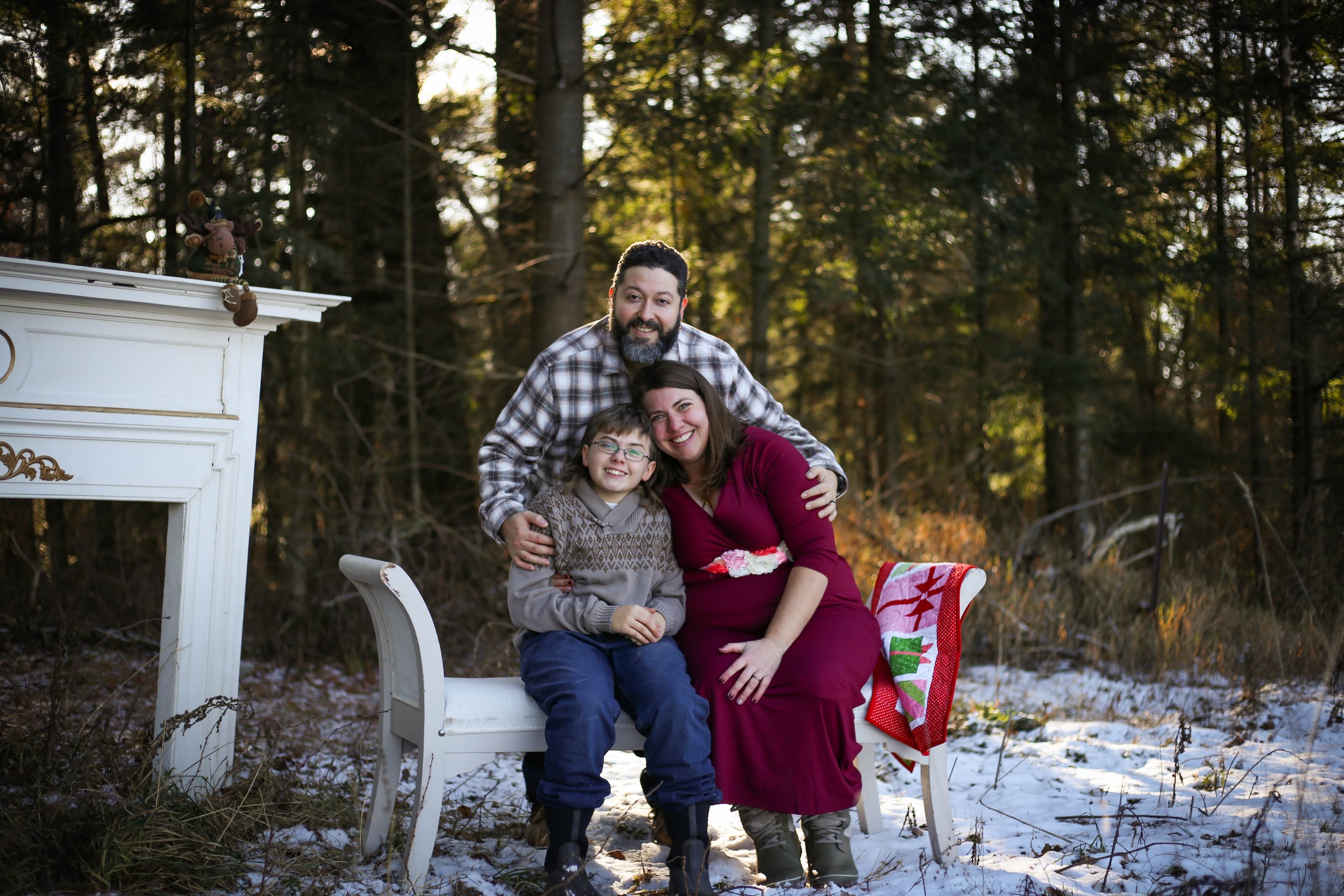 A picture of owners Julie and Eduardo with their son and forest back drop