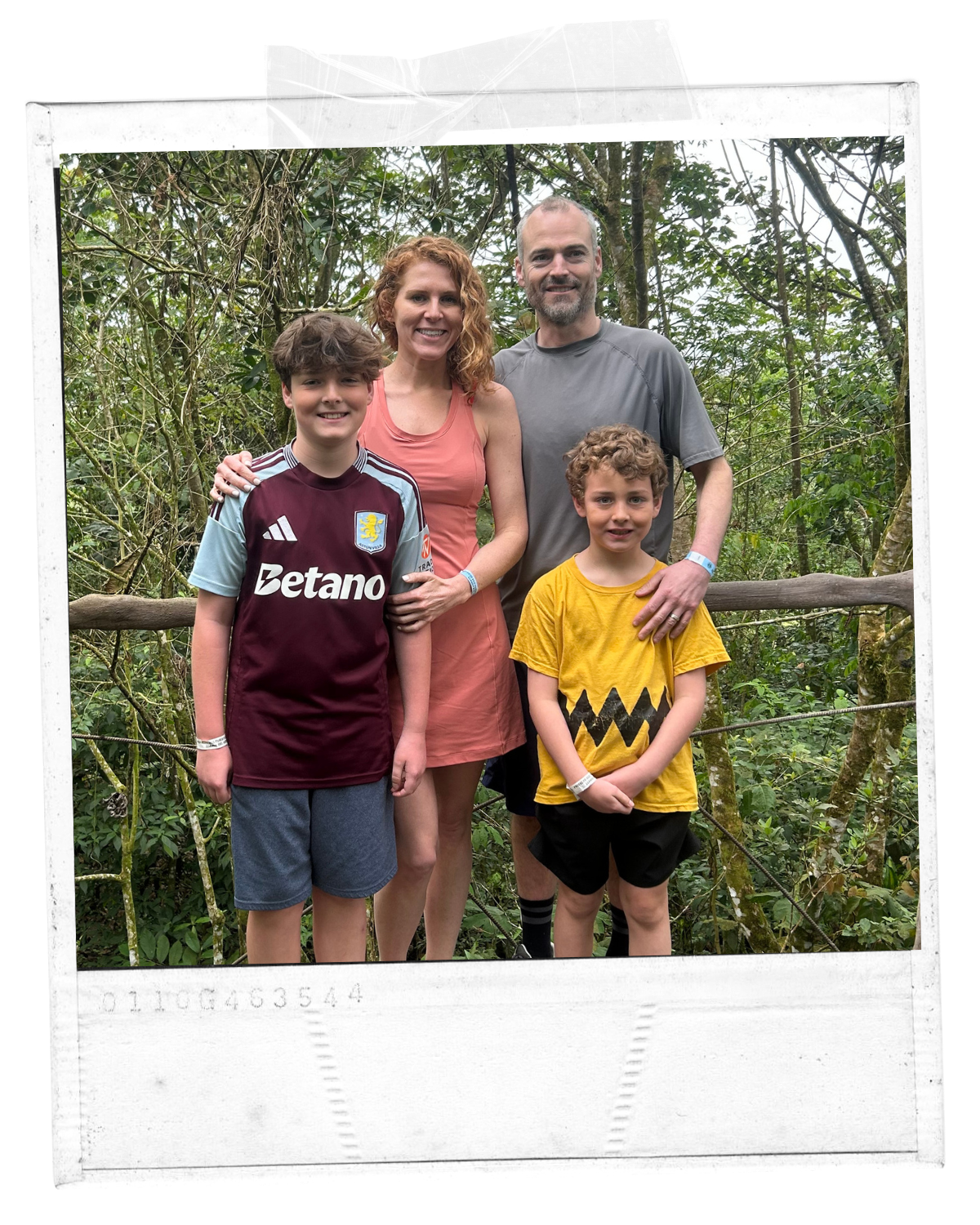 A family of five posing for a photo outdoors in a lush, green forest.