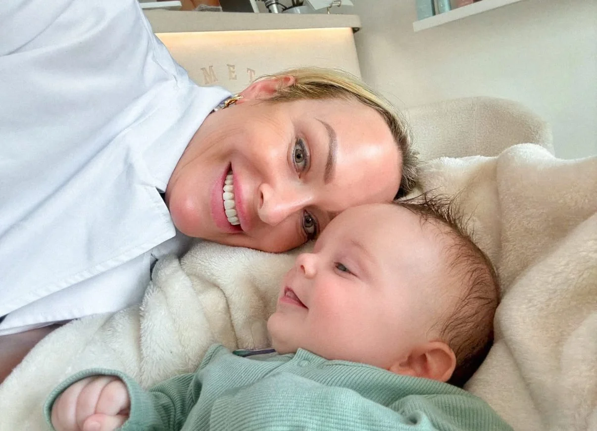 A woman and a young boy lying on a bed, facing each other, smiling and gazing into each other's eyes.