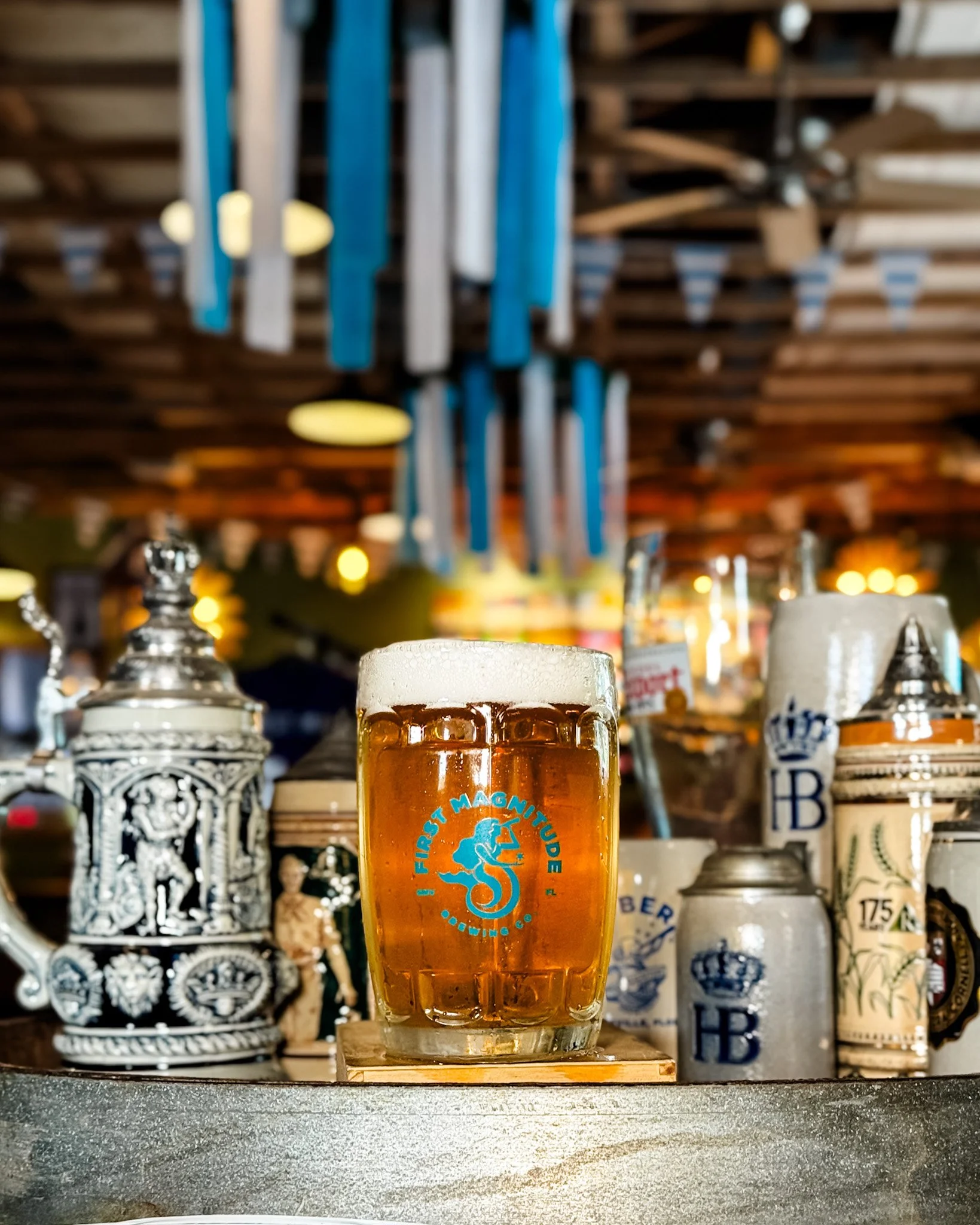 full first magnitude glass stein with amber colored beer surrounded by Oktoberfest steins.