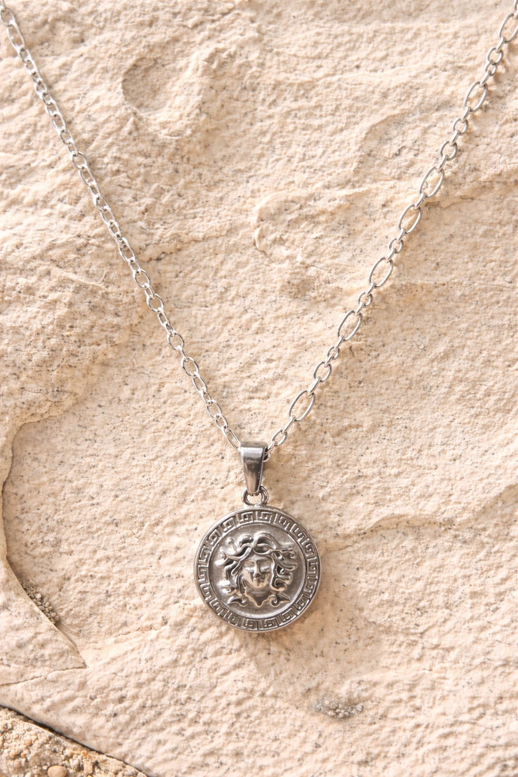Silver Medusa pendant on beige background.png