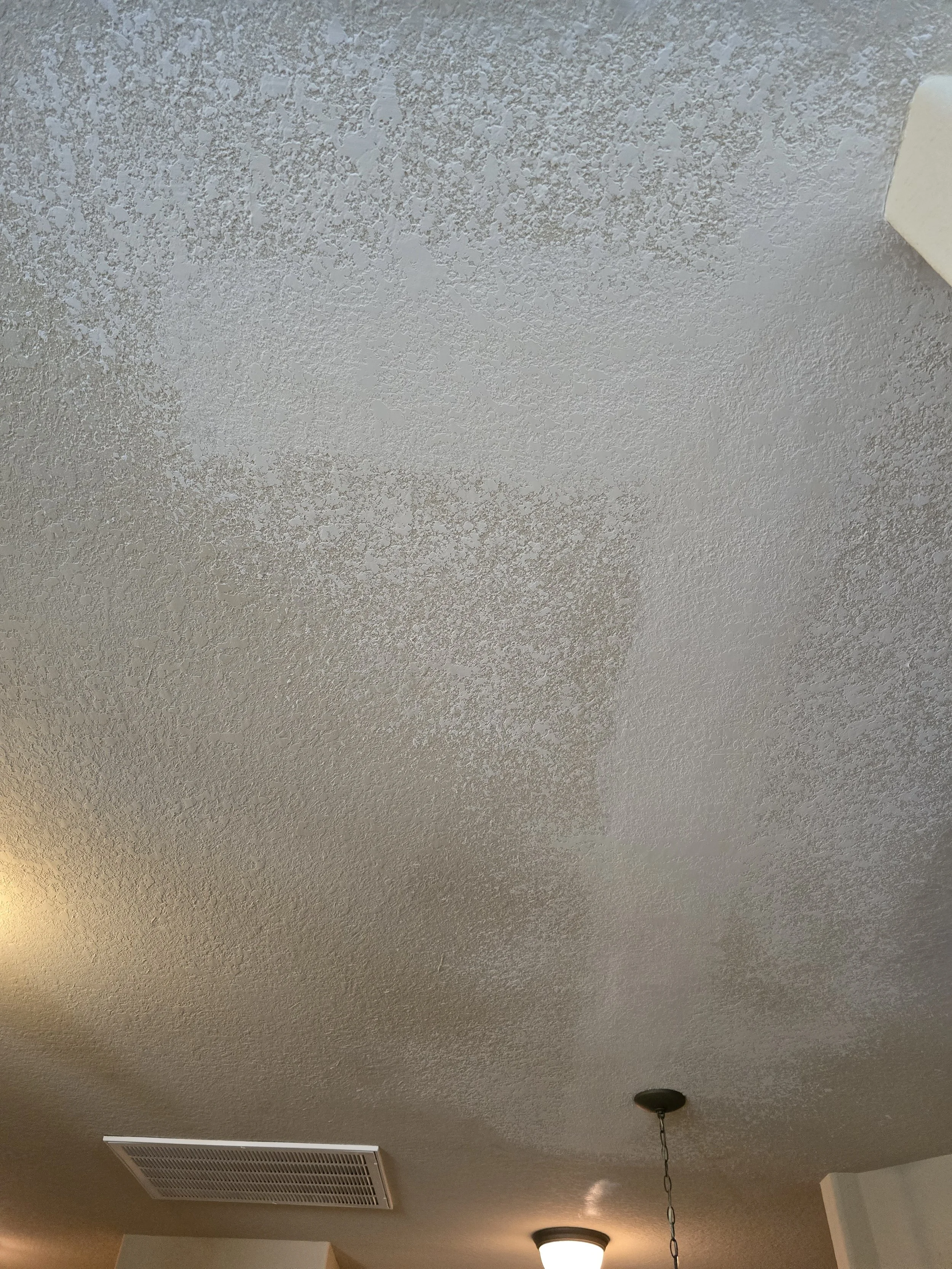 Ceiling with noticeable water stains and discoloration in a room.