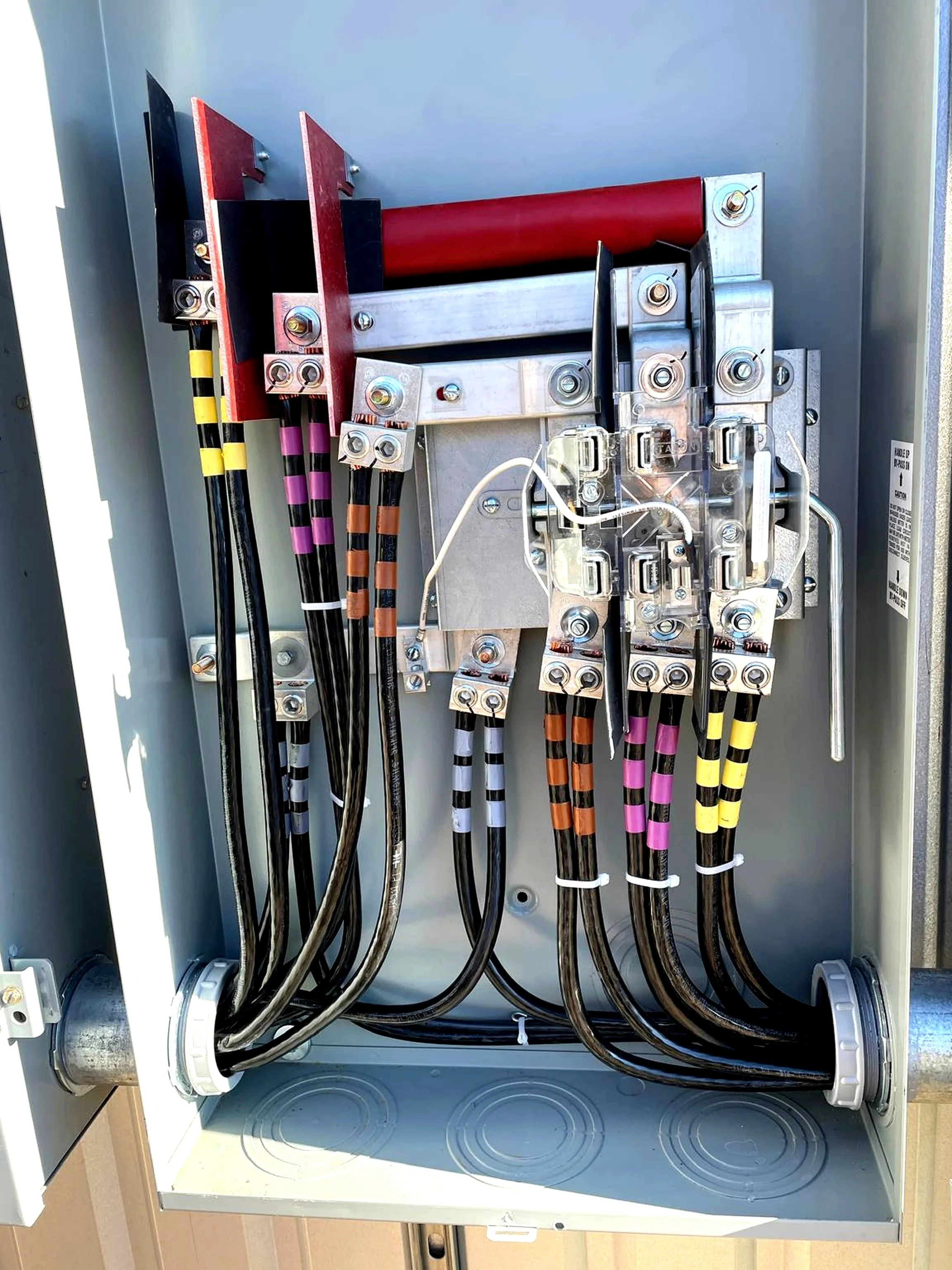 An electrical control panel with wires and components inside an outdoor metal box.